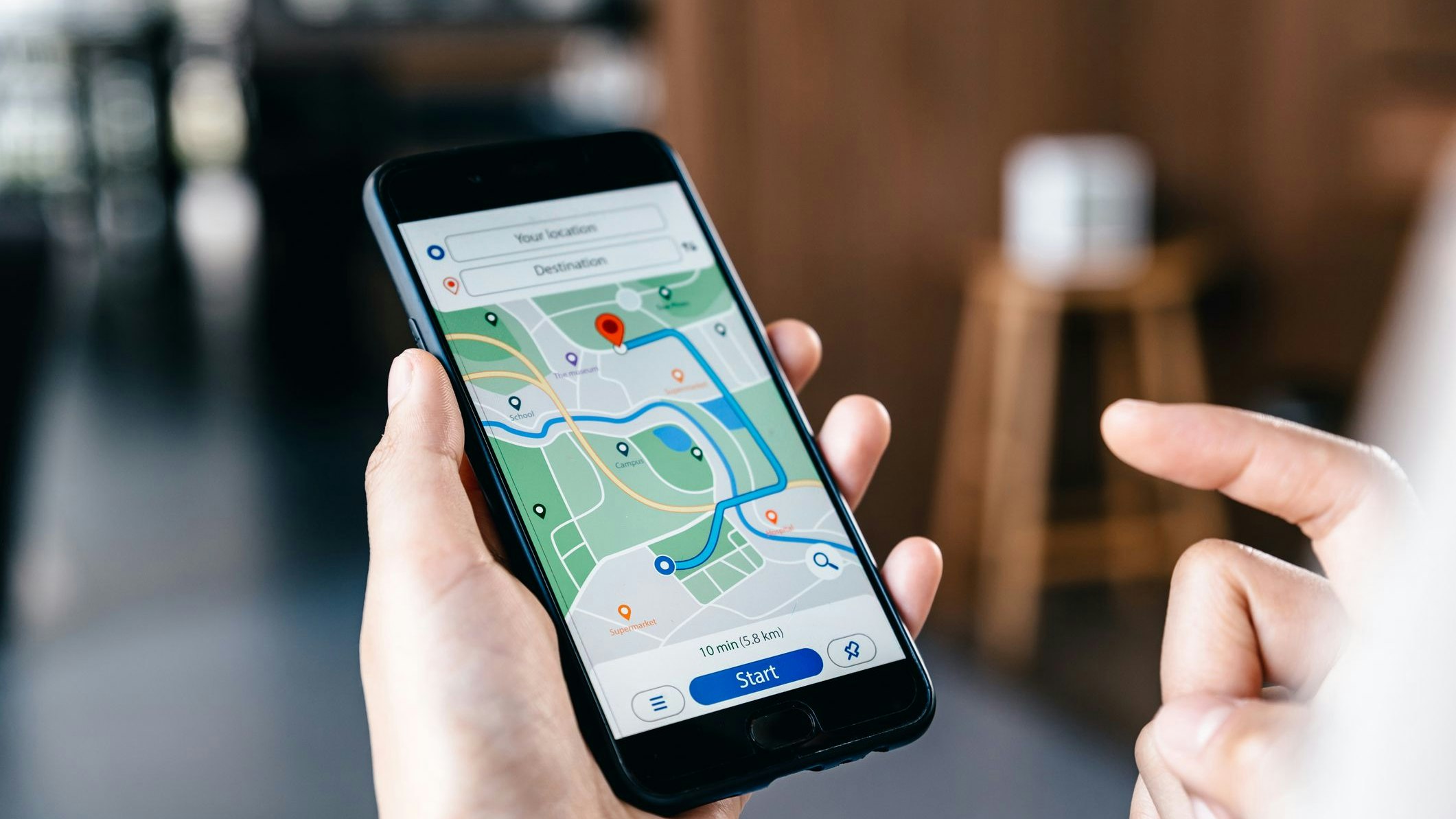 Hand of young woman searching location in map online on smartphone.