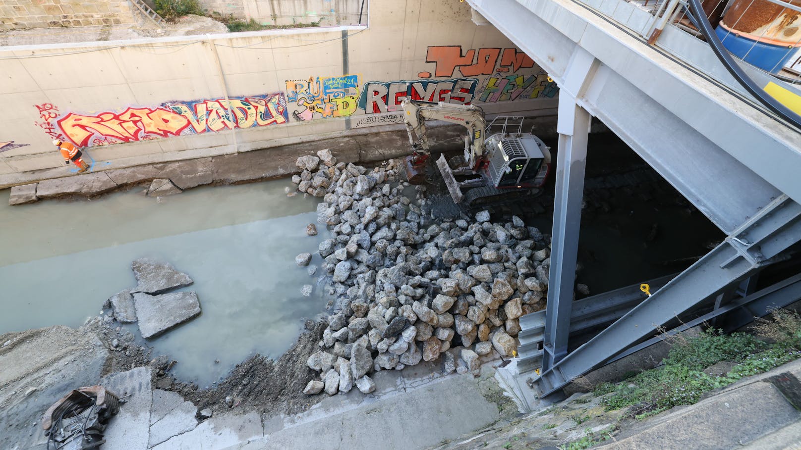 Im Fluss wird ein Steinwall errichtet, um das Wasser aufzustauen