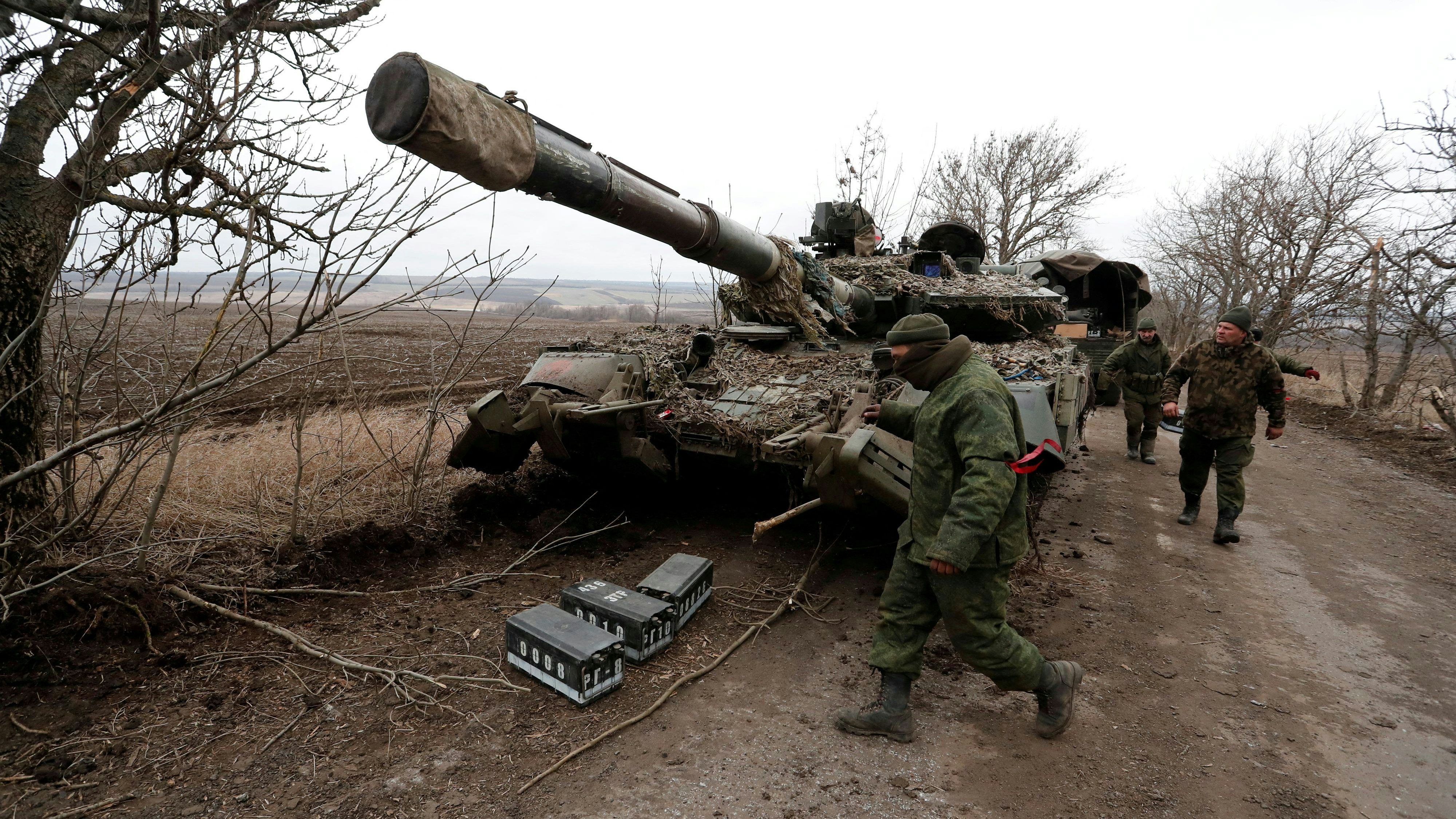 FILE PHOTO: Pro-Russian separatists walk near an abandoned tank on a road between the separatist-controlled settlements of Mykolaivka (Nikolaevka) and Buhas (Bugas), as Russia's invasion of Ukraine continues, in the Donetsk region, Ukraine March 1, 2022. REUTERS/Alexander Ermochenko/File Photo