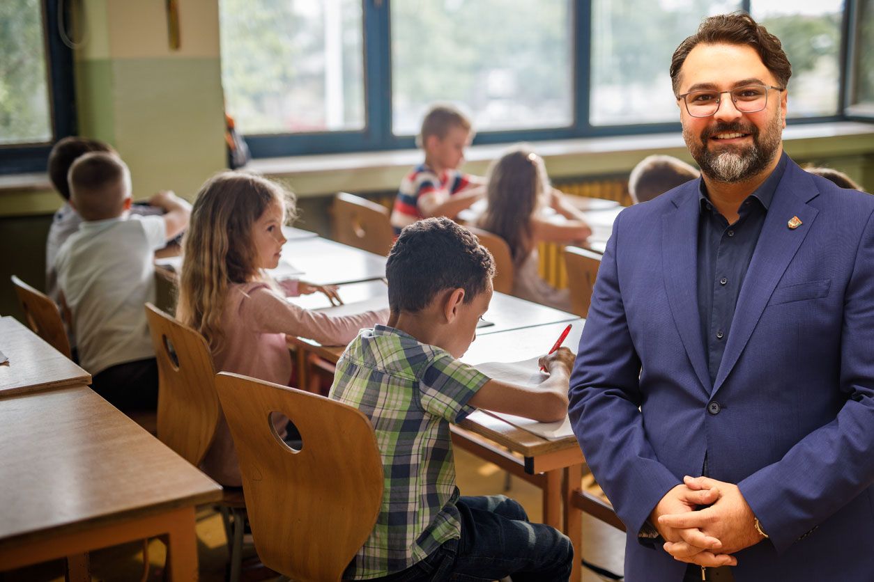 Large group of school kids writing on a class in the classroom. Focus is on boy in the foreground.