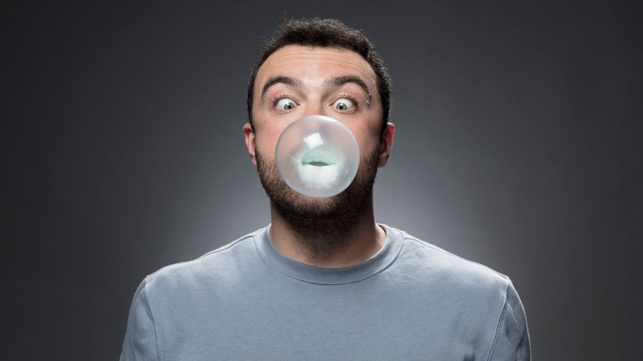 Guy blowing up a bubble.Young Man chewing a gum and blowing bubble