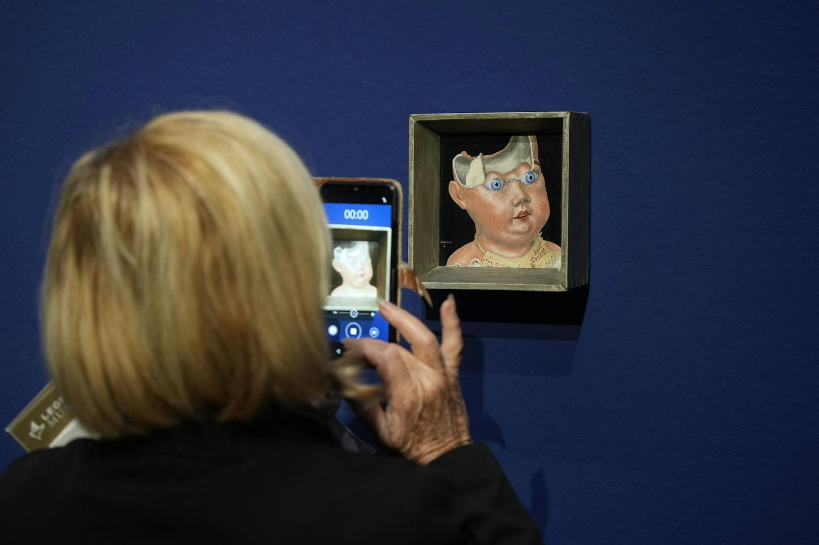 Eine Frau fotografiert den "Zebrochenen Puppenkopf" von Rudolf Wacker im Leopoldmuseum.