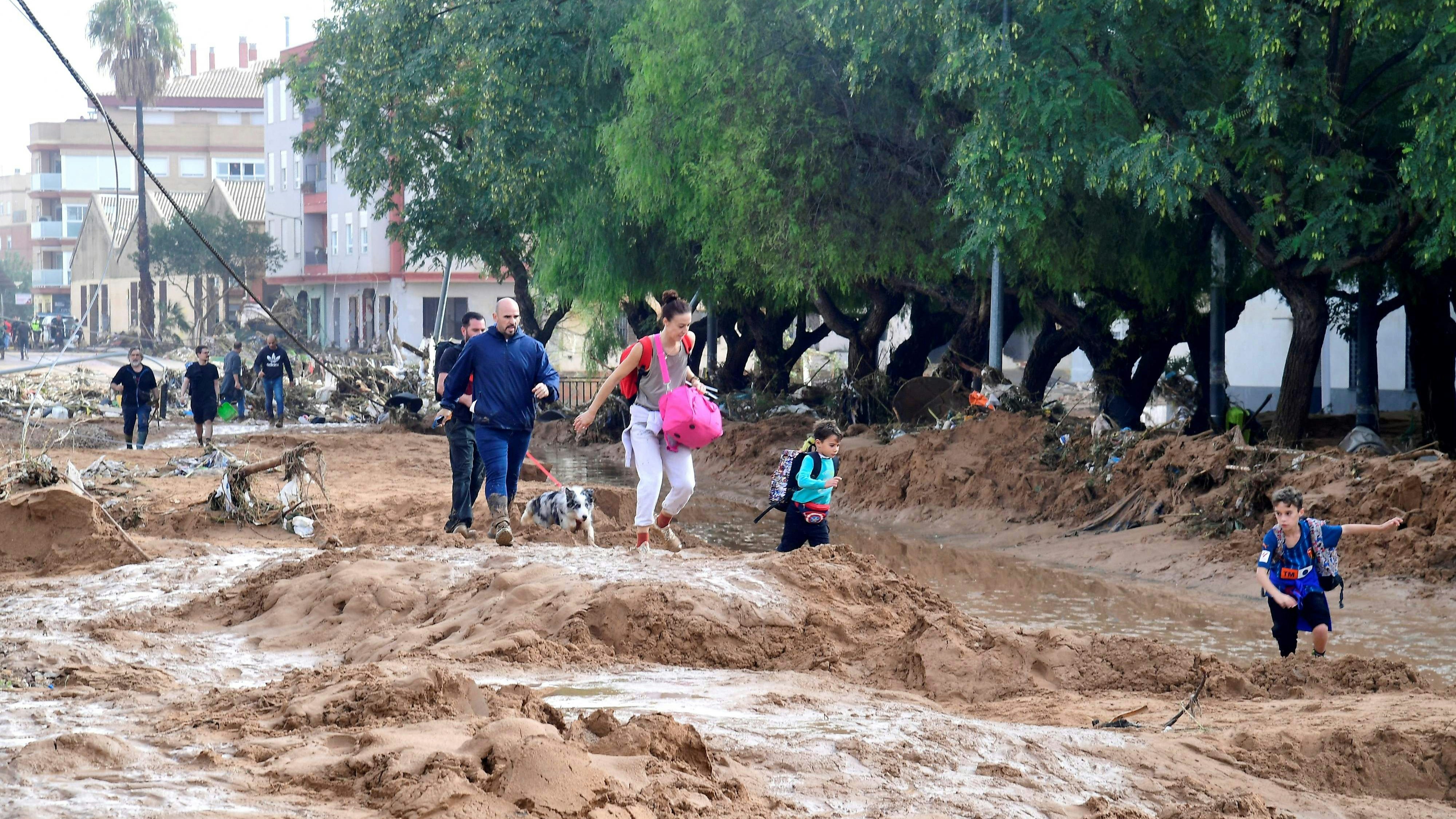 Eine Familie kämpft sich durch den Schlamm, den die Fluten in Picanya, südwestlich von Valencia, hinterlassen haben