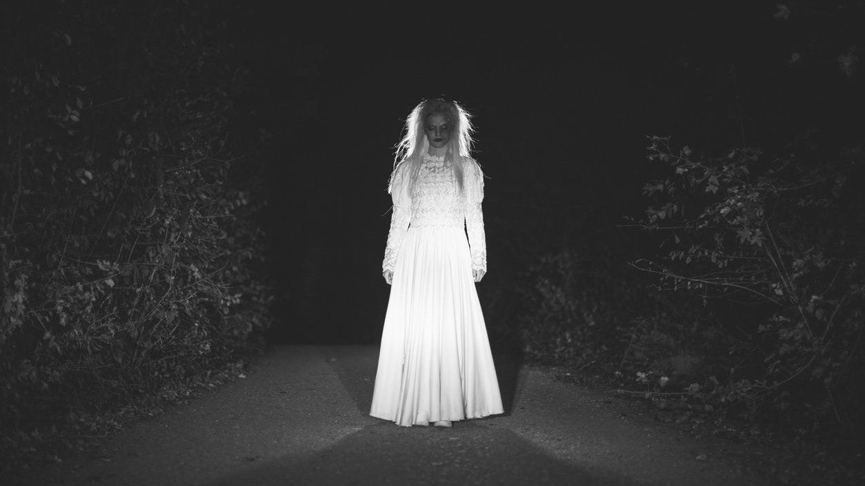 One woman, she masked herself in a scary witch for halloween, standing on the street, black and white.