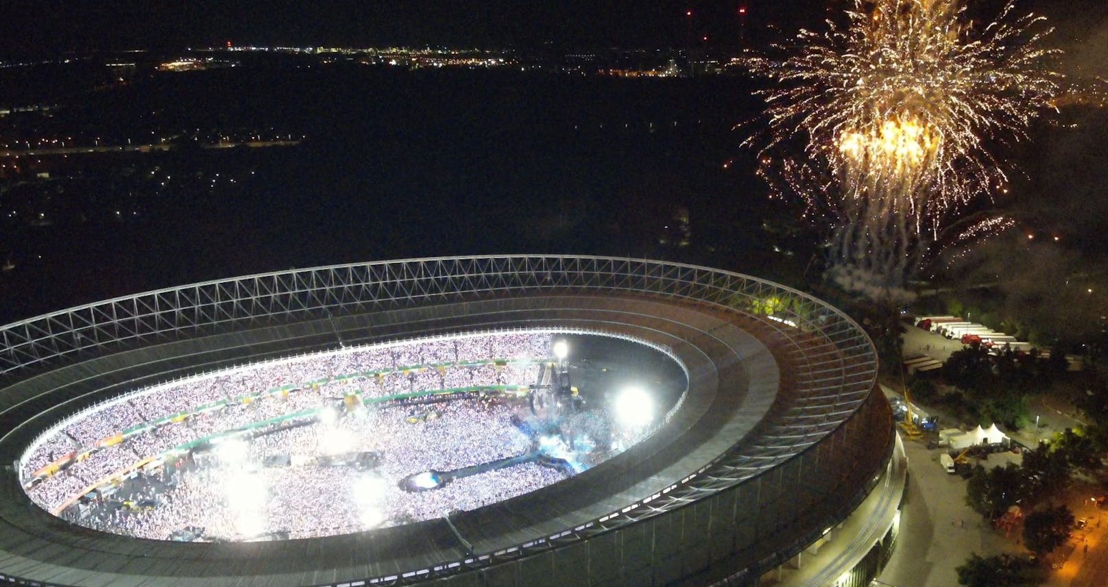 Luftaufnahme des beleuchteten Ernst-Happel-Stadions während des Coldplay-Konzerts. Die Drohne überwacht die Menschenmengen.