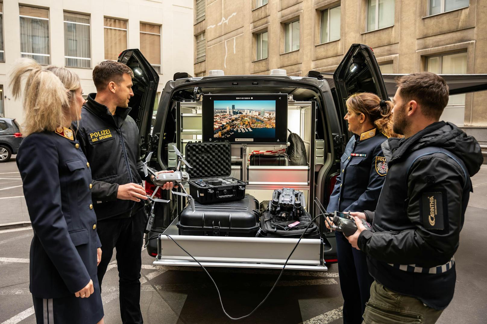 Das Drohnen-Team zeigt den neuen Einsatzwagen mit großem Bildschirm für Live-Übertragungen. Polizisten besprechen den nächsten Einsatz.