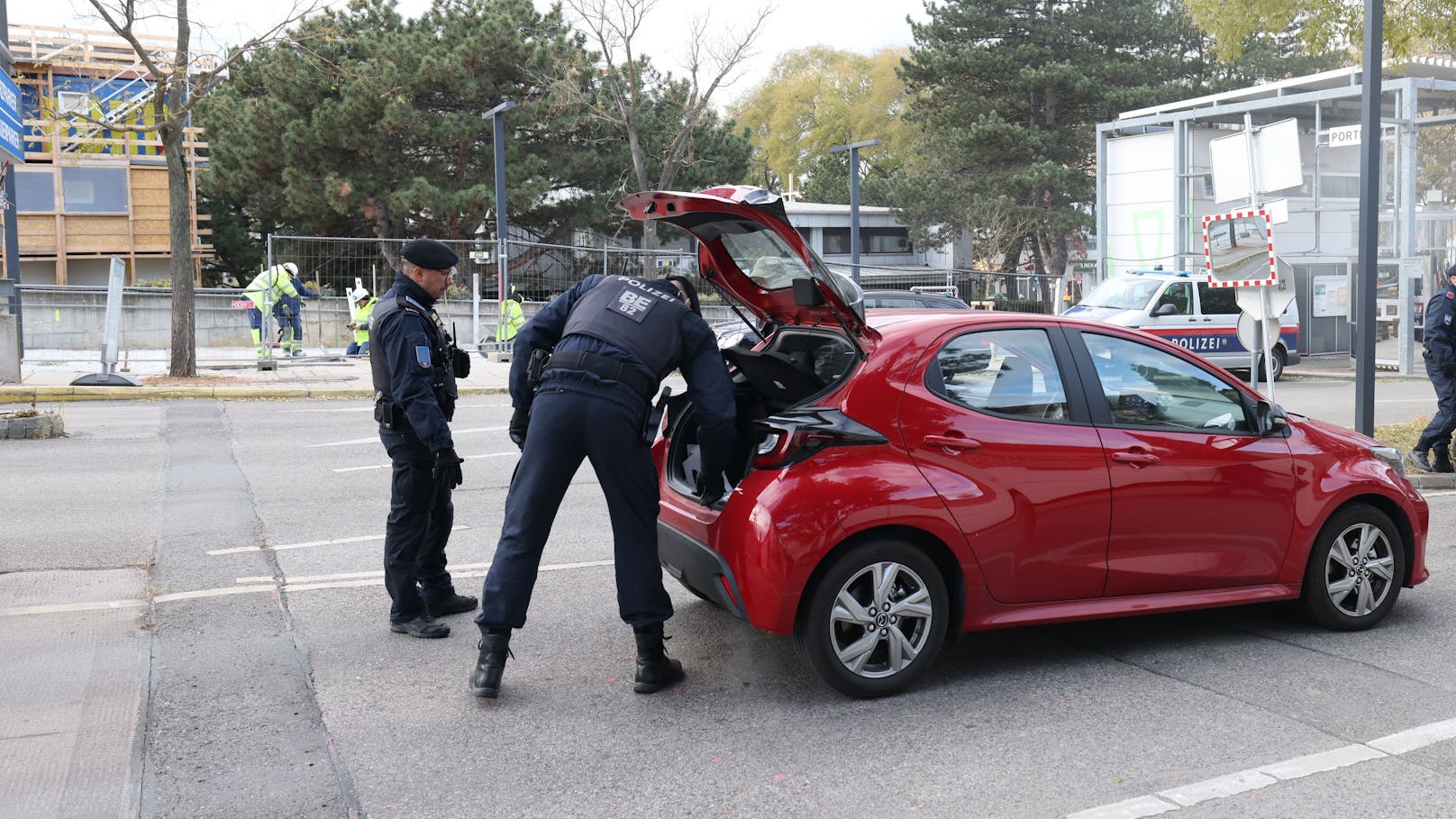 Beamte durchsuchen Kofferräume von Fahrzeugen.