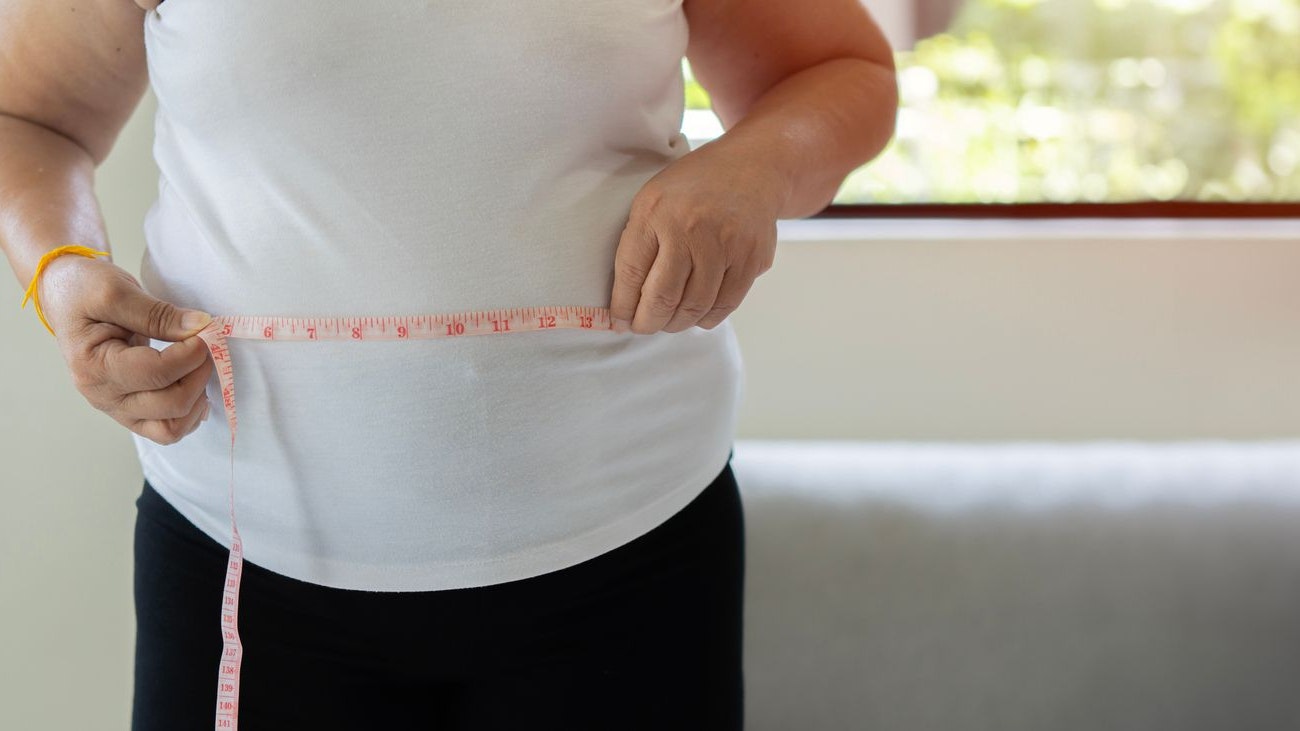 Senior woman measuring waist with tape at home. Elderly overweight woman checking out her body measuring big stomach. Lose weight, slimming, dieting, health care concept