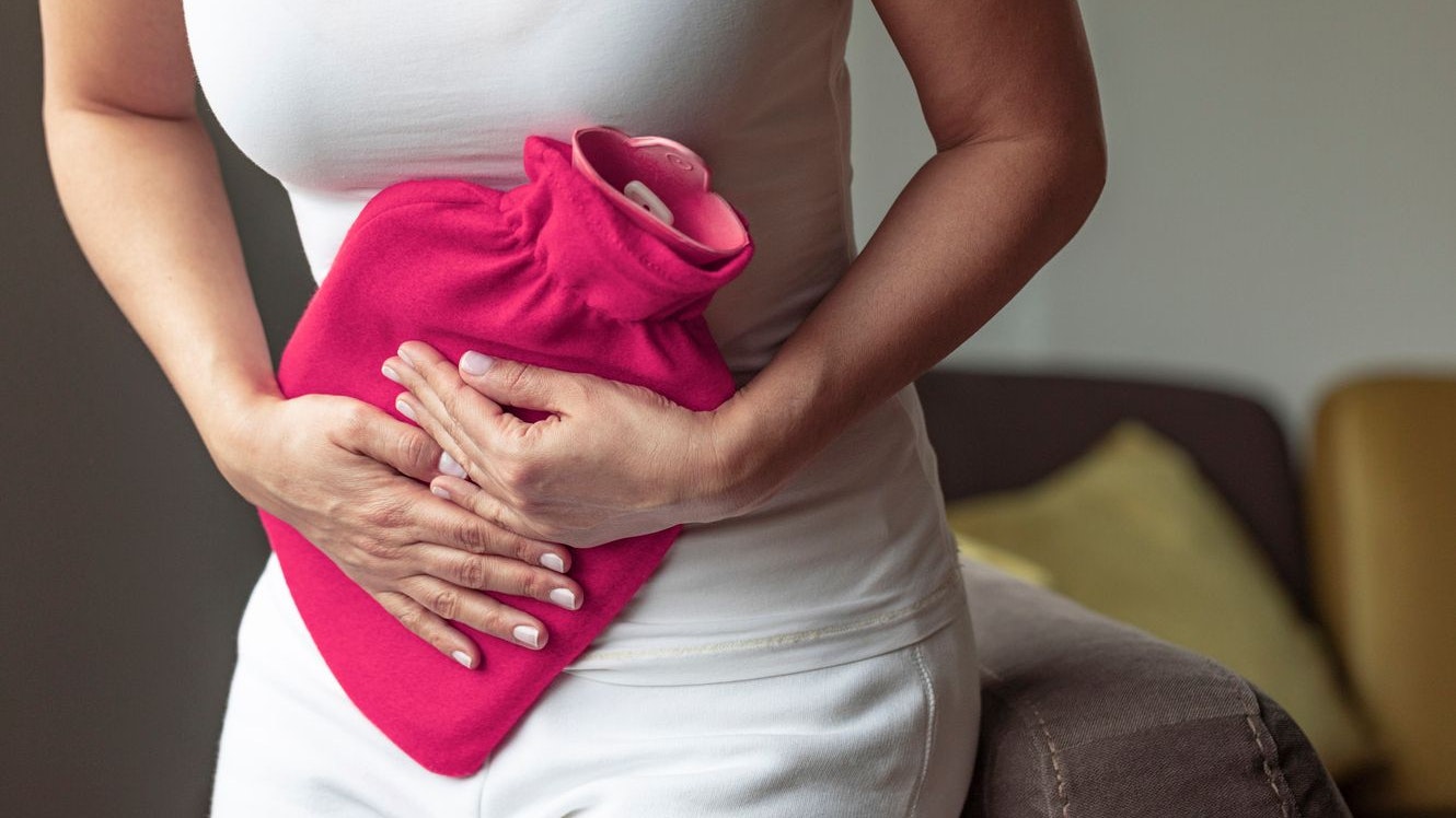 Unhealthy young woman with stomachache using a hot water bag.
