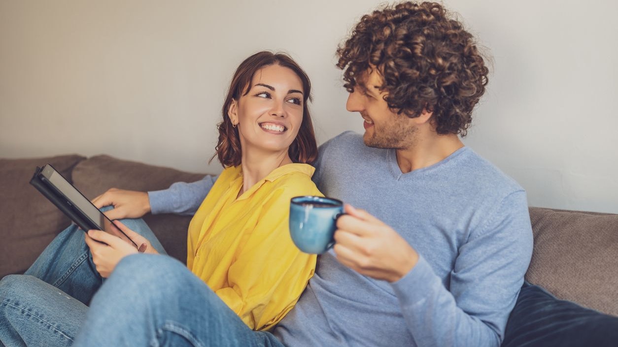 Portrait of young happy couple at home. They are relaxing at sofa.