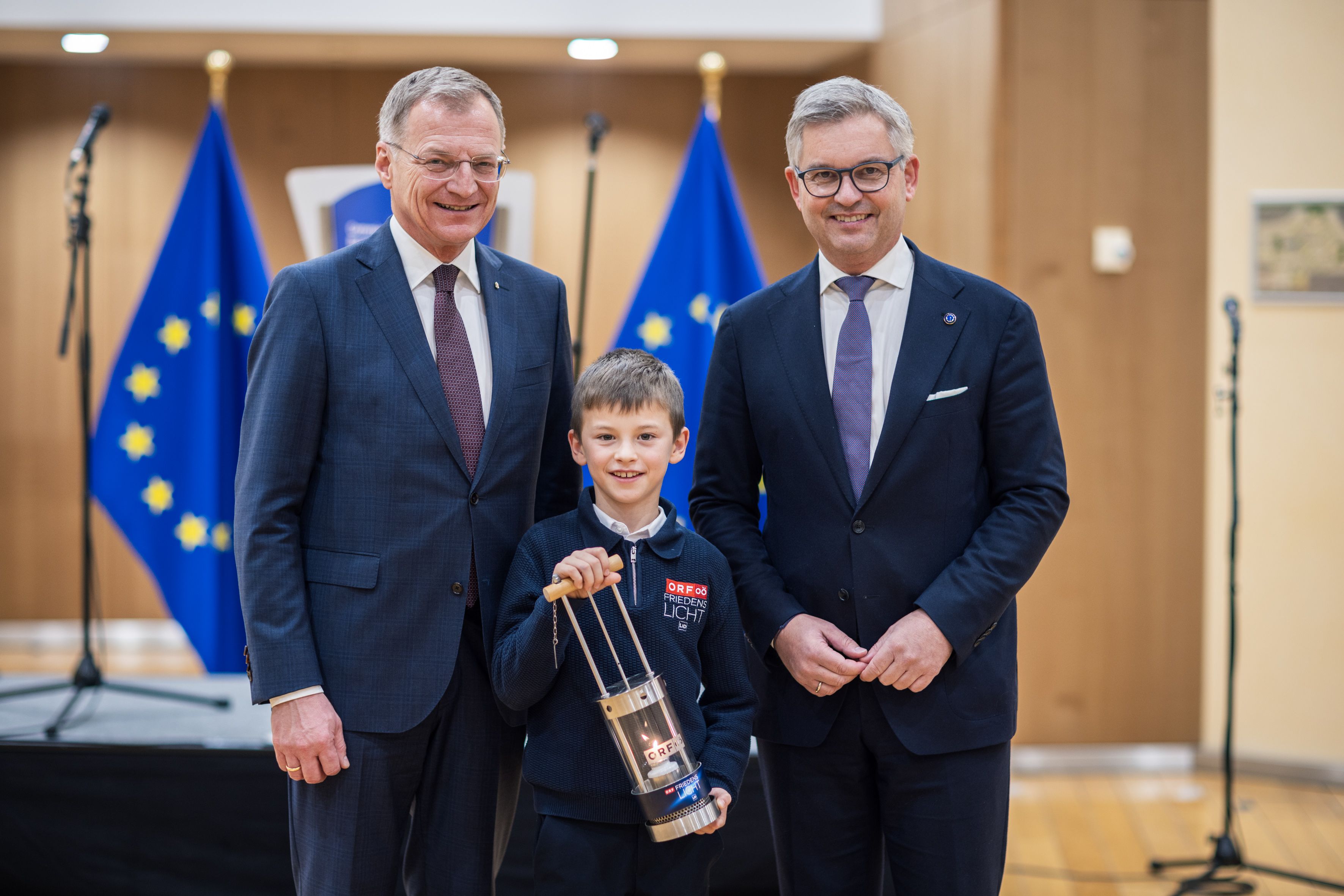 Der neunjährige Matthias (Mitte) überreichte in Begleitung von Landeshauptmann Thomas Stelzer (li.) das Friedenslicht an EU Kommissar Magnus Brunner (re.).