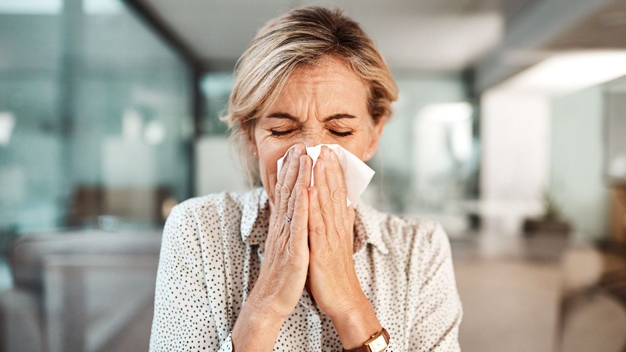 Shot of a mature businesswoman blowing her nose while working in an office
