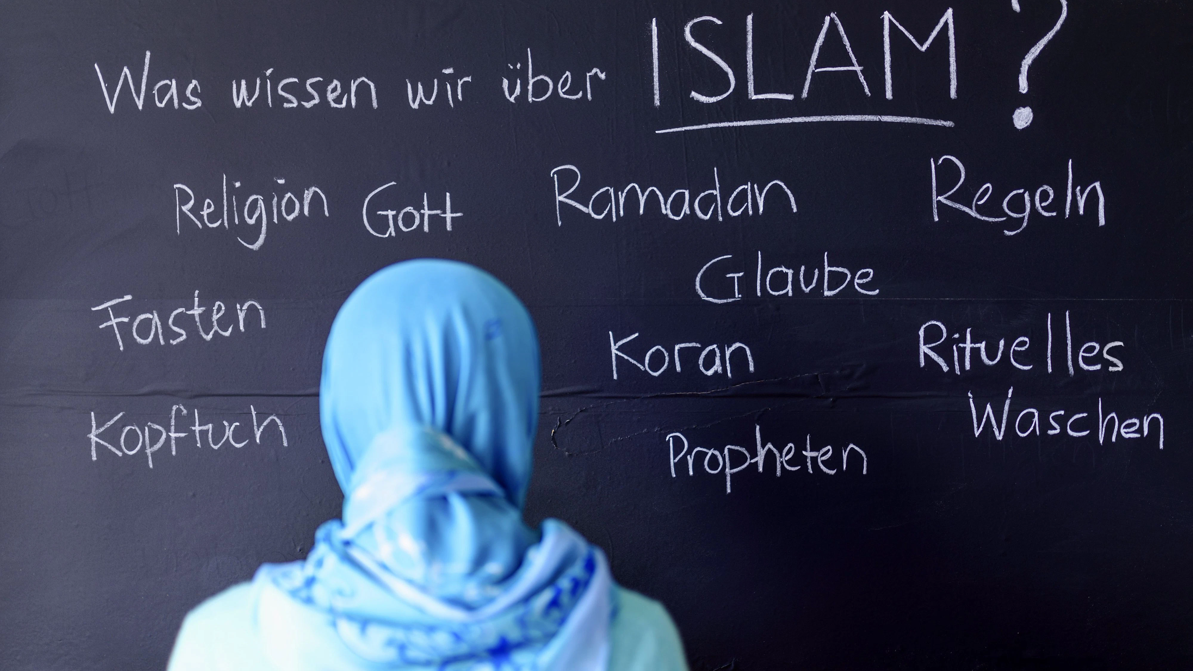 Eine muslimische Schülerin vor einer Tafel mit Begriffen aus dem Islam im Islamunterricht. (Themenbild, Symbolbild) 