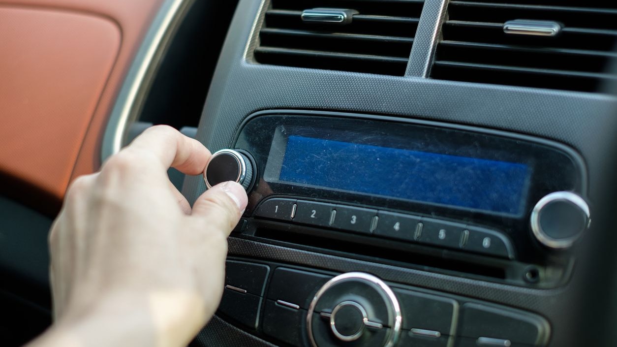 Man hand adjusting dial button car audio control