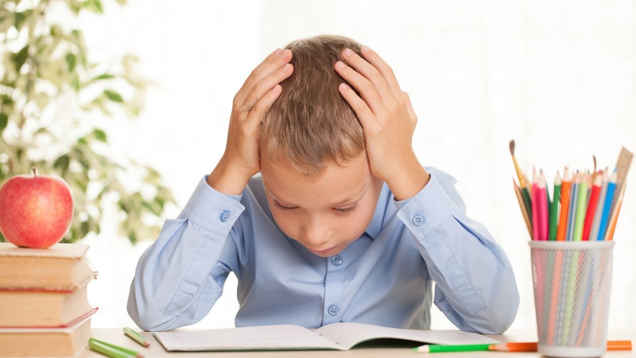 Young schoolboy sitting at the table and doing homework. Elementary education concept