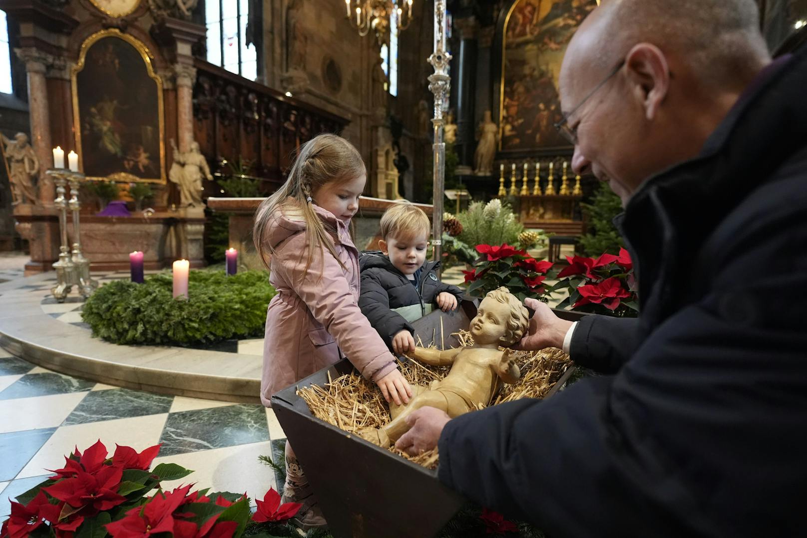 Während der Messe zu Weihnachten wird das Jesuskind von dem kleinsten Ministranten zur Krippe getragen.