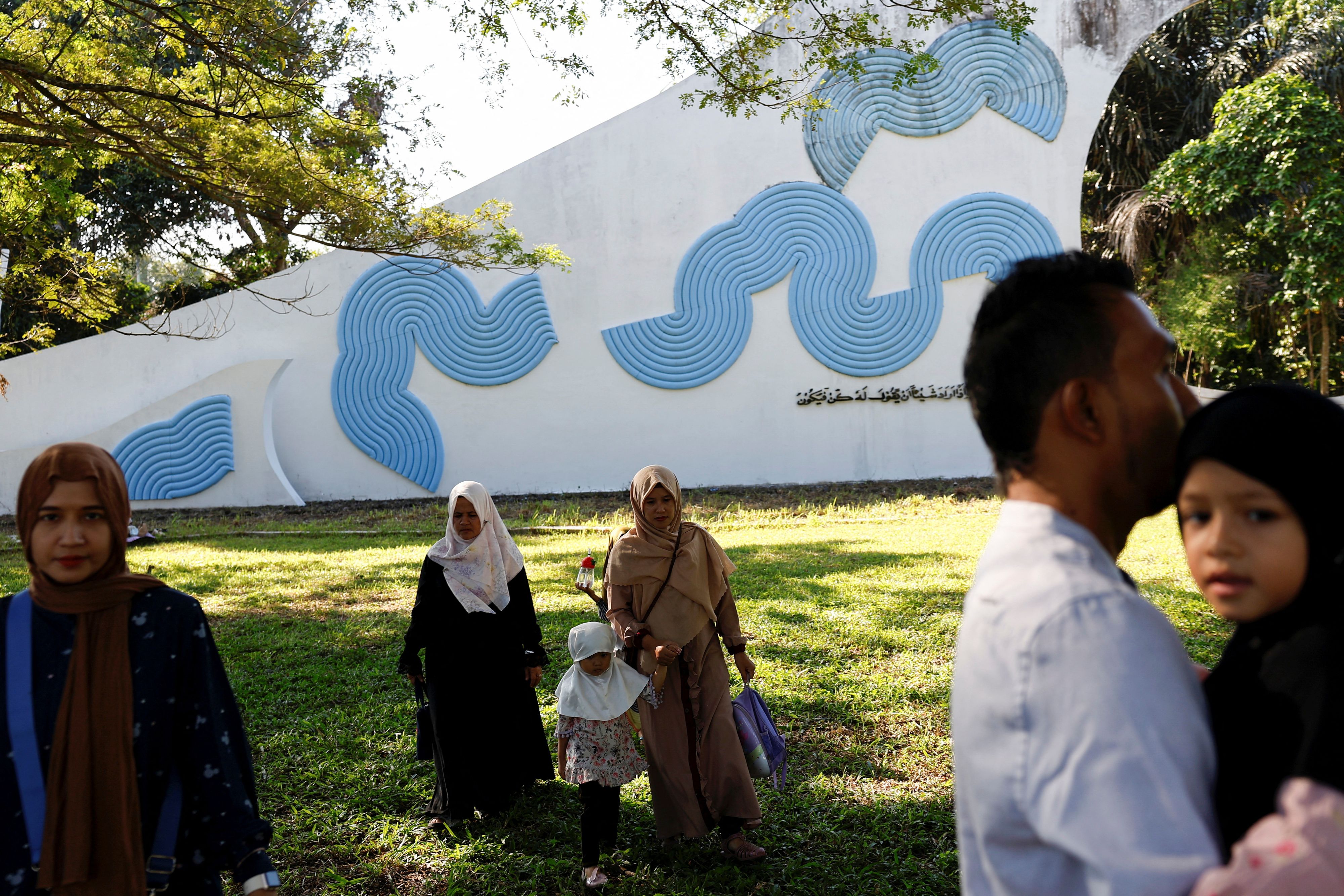 Menschen zu Besuch am Siron-Massengrab, wo die Opfer des Tsunamis von 2004 begraben sind.