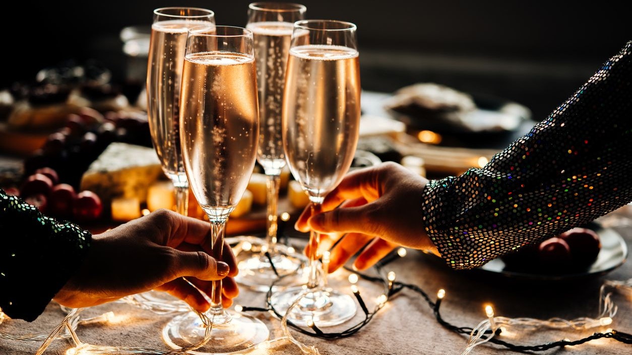 Friends celebrating Christmas or New Year eve party with champagne or sparkling wine.