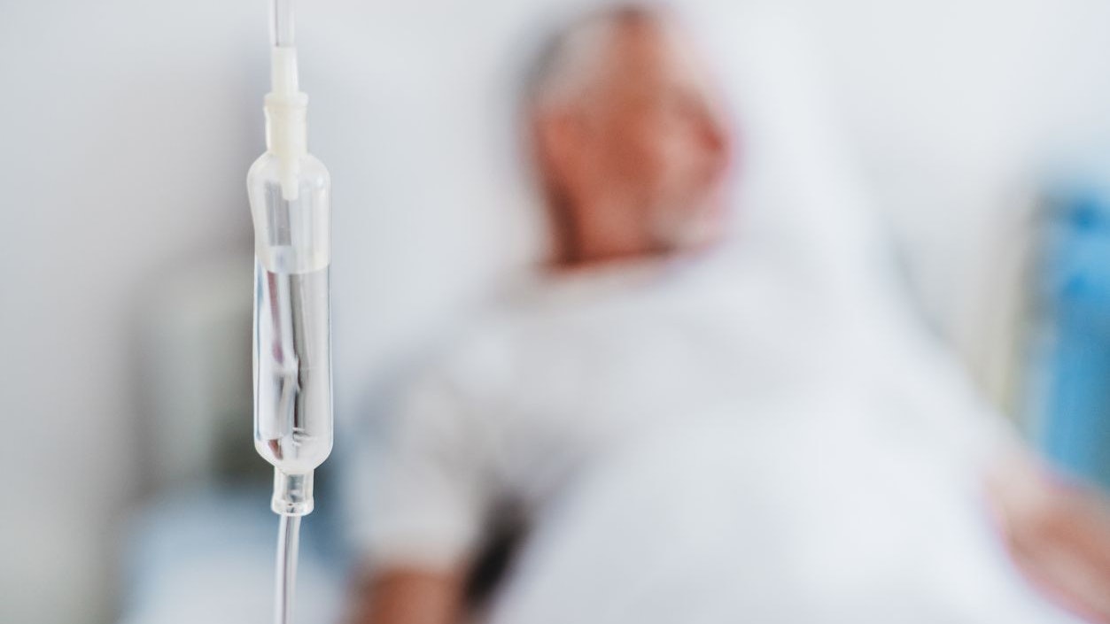 Close up shot of medicine in and iv drip and patient on background in hospital room