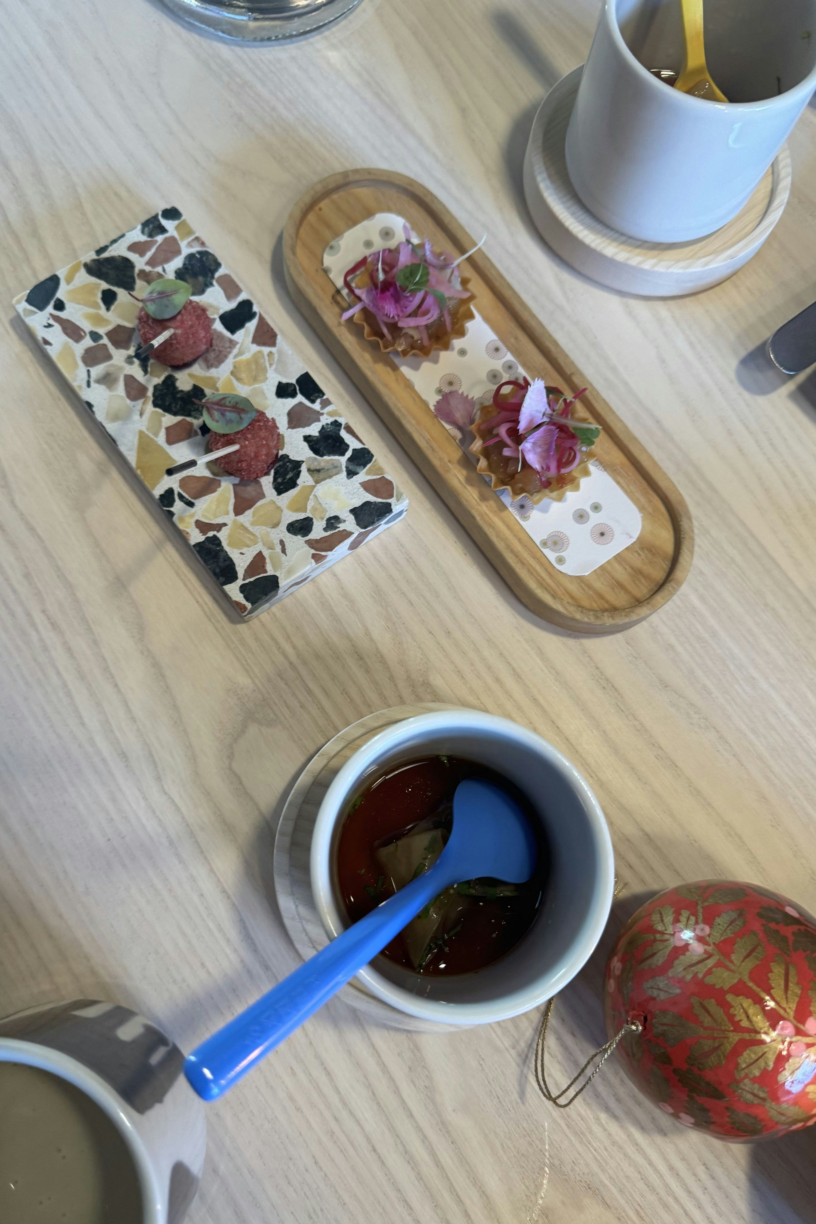 Consommé mit Beinfleisch-Tascherl und Zwiebelöl, Garnelen-Tartelette mit roten Rüben und Gänseleber-Praline mit Himbeeren