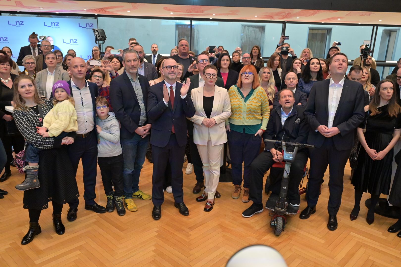 Die Spitzenkandidaten wenige Sekunden nach Bekanntgabe der ersten Hochrechnung. Von links: Martin Hajart (ÖVP) mit Familie, Lorenz Potocnik (Linz+), Dietmar Prammer (SPÖ), Eva Schobesberger (Grüne), Gerlinde Grünn (KPÖ), Georg Redlhammer (Neos), Michael Raml (FPÖ) mit Ehefrau.