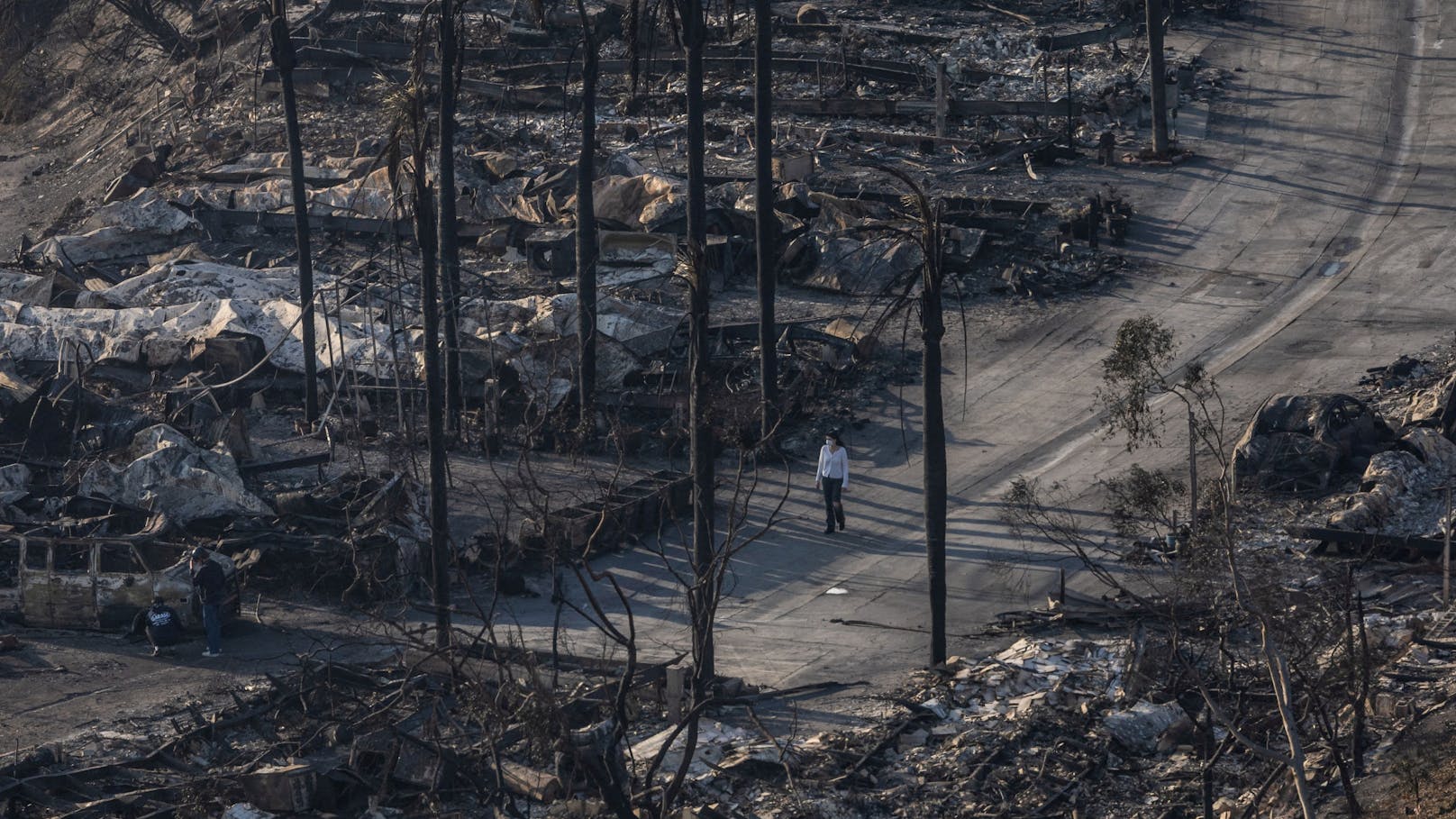 Eine Frau geht an den Überresten von Häusern vorbei, die durch das Palisades-Feuer im Stadtteil Pacific Palisades.