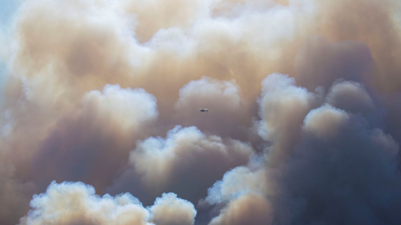 Ein Hubschrauber fliegt an den Rauchschwaden vorbei, während die Bewohner weiterhin vor dem Palisades Fire fliehen.