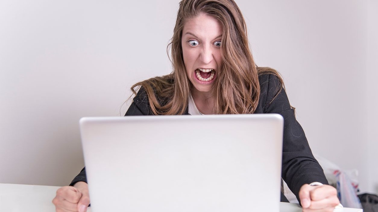Angry furious business woman yelling at her laptop in her office