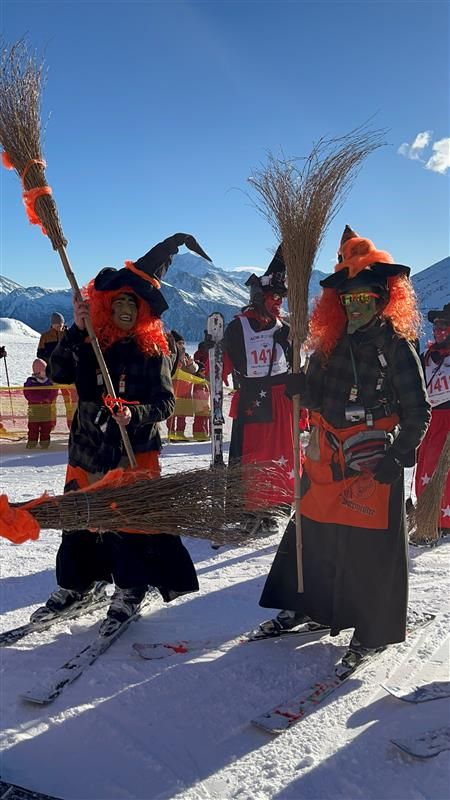 Menschen verkleiden sich als Hexen und fahren die Piste hinab.