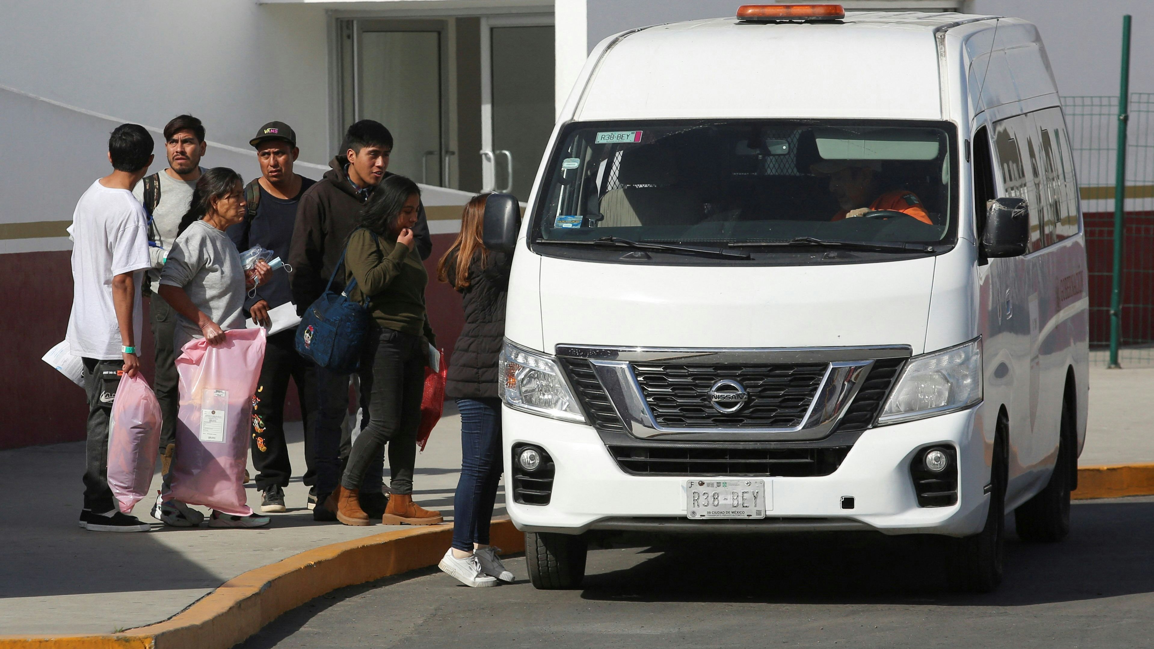 Aus den USA abgeschobene Migranten besteigen am Grenzübergang El Chaparral in Tijuana, Mexiko, einen Lieferwagen des mexikanischen Nationalen Migrationsinstituts