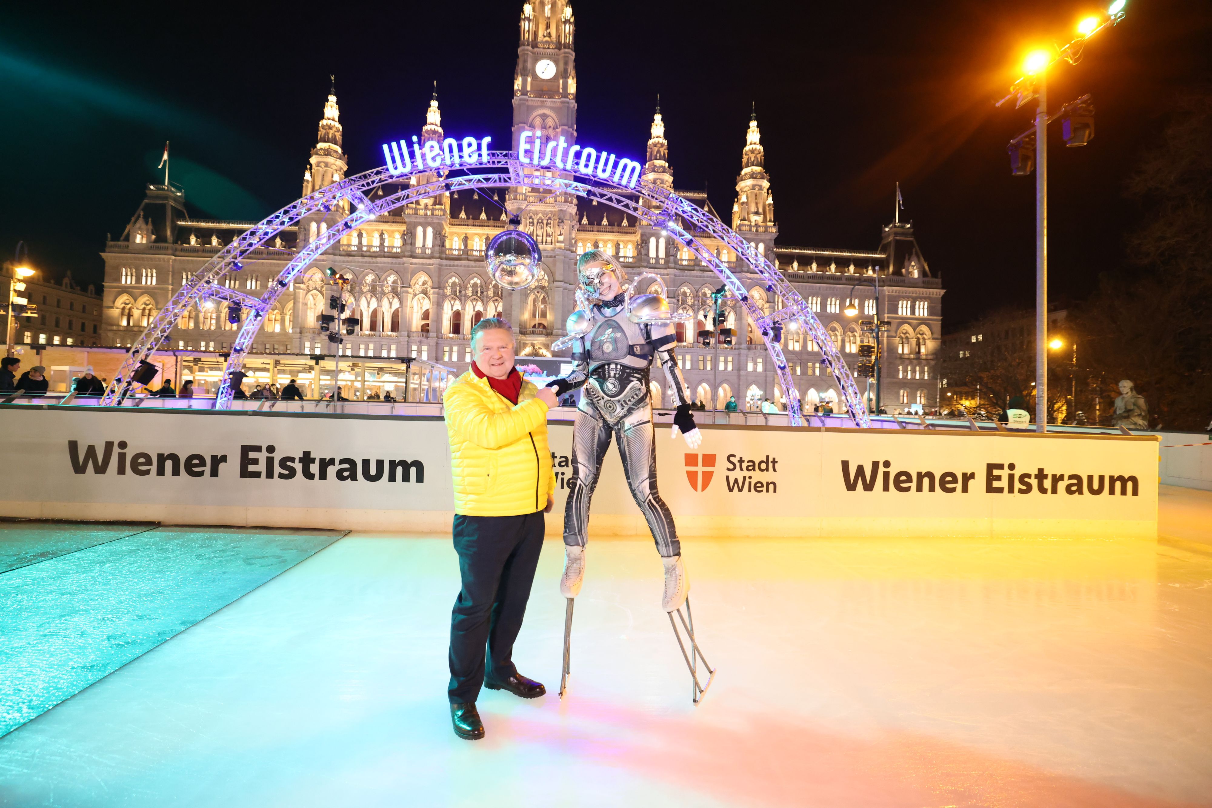 Bürgermeister Michael Ludwig und der futuristische Performer vor der ikonischen Eistraum-Kulisse am Rathausplatz.