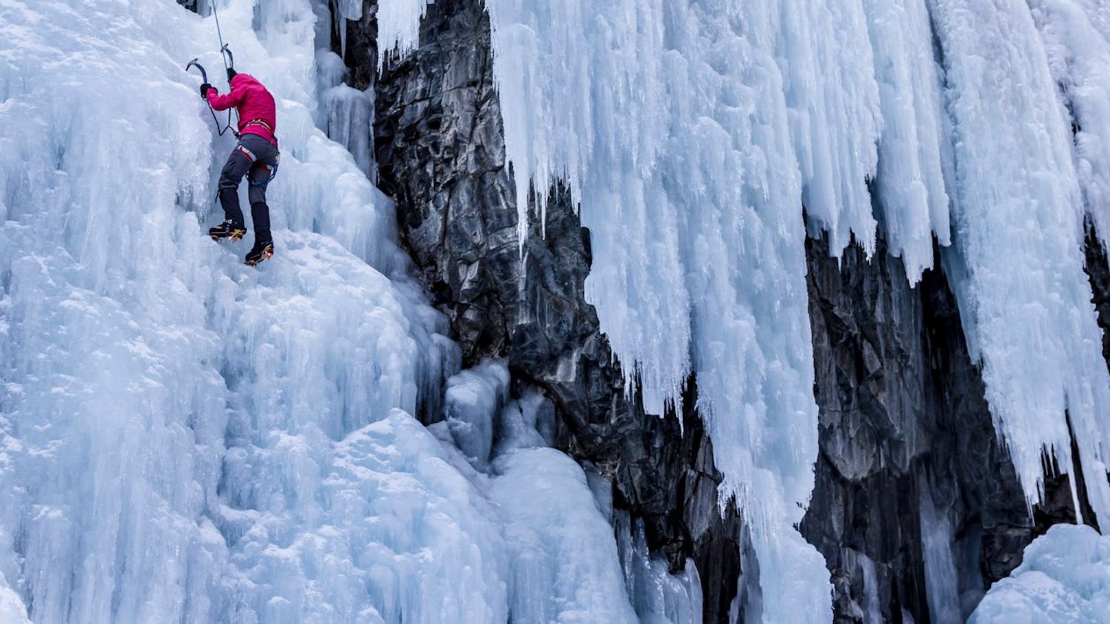 Männer klettern Eis-Wasserfall hoch und brauchen Hilfe