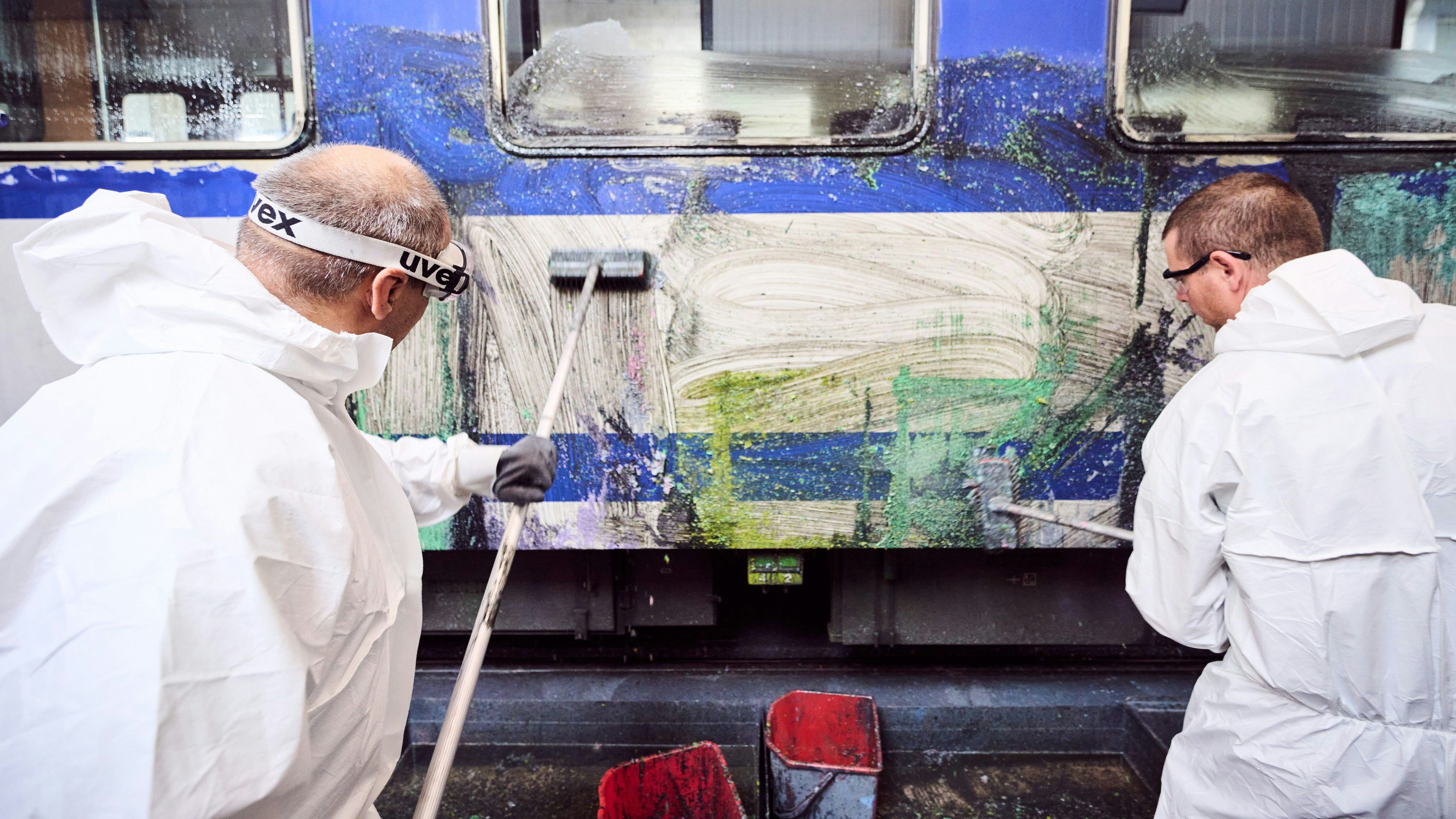 Personal beim Reinigen eines Zugs von Graffiti