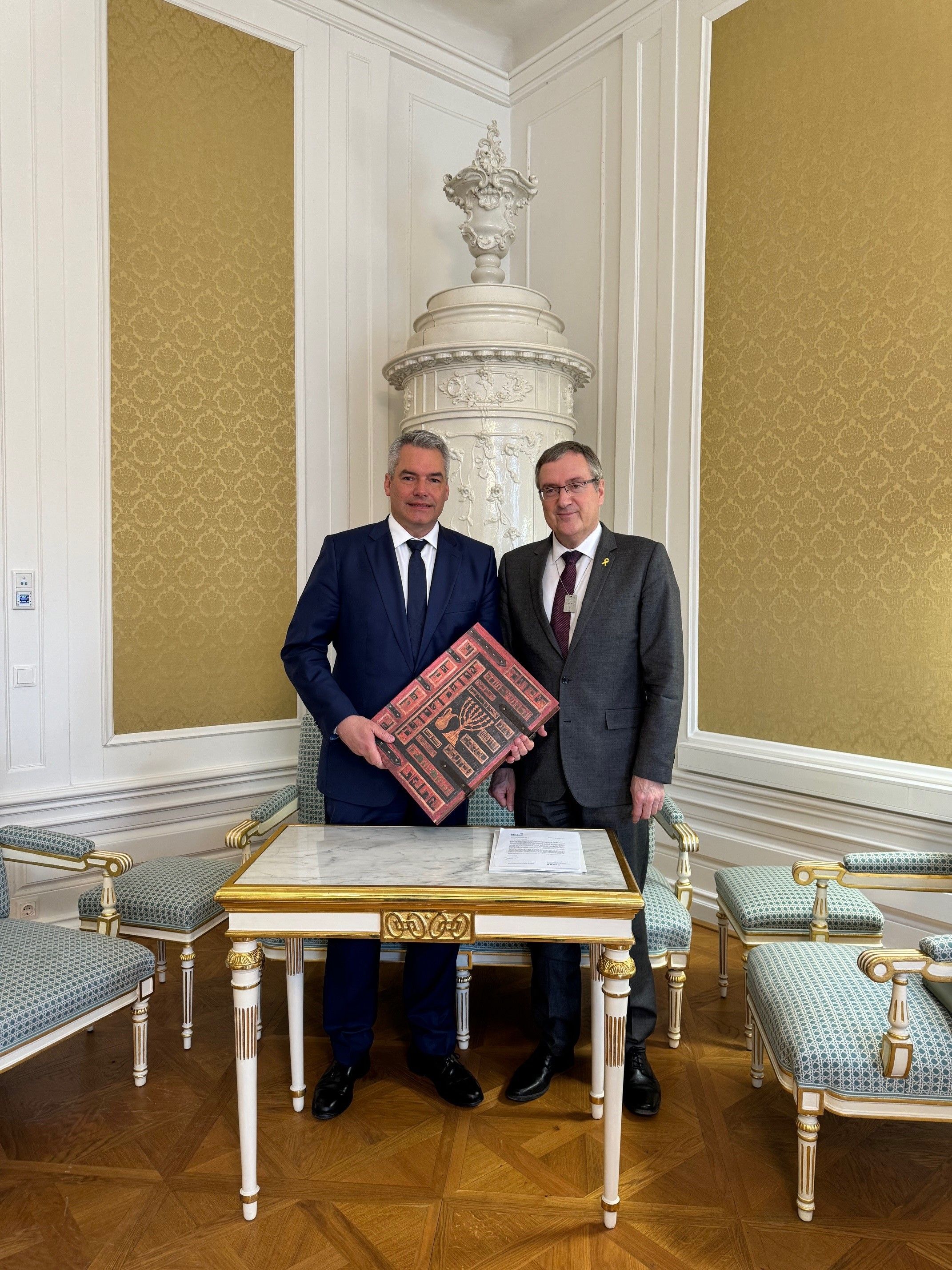 Ex-Kanzler Nehammer und der Botschafter David Roet bei der Übergabe mit der Bibel.