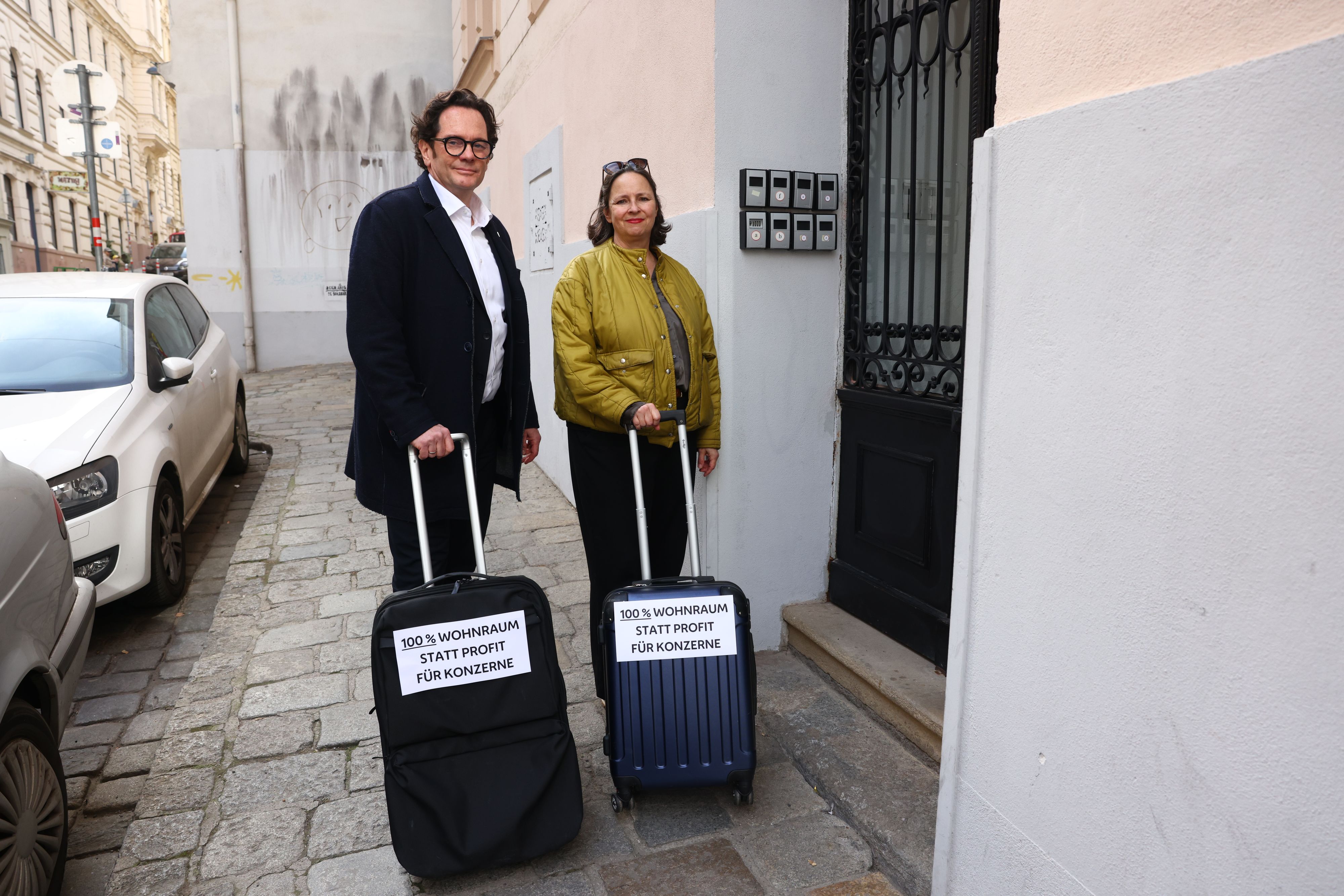 Bezirksvorsteher Markus Reiter und Stellvertreterin Isabelle Uhl zeigen symbolisch ihre Forderung nach einem Verbot von Airbnb in Neubau – mit Rollkoffern, die die Botschaft 