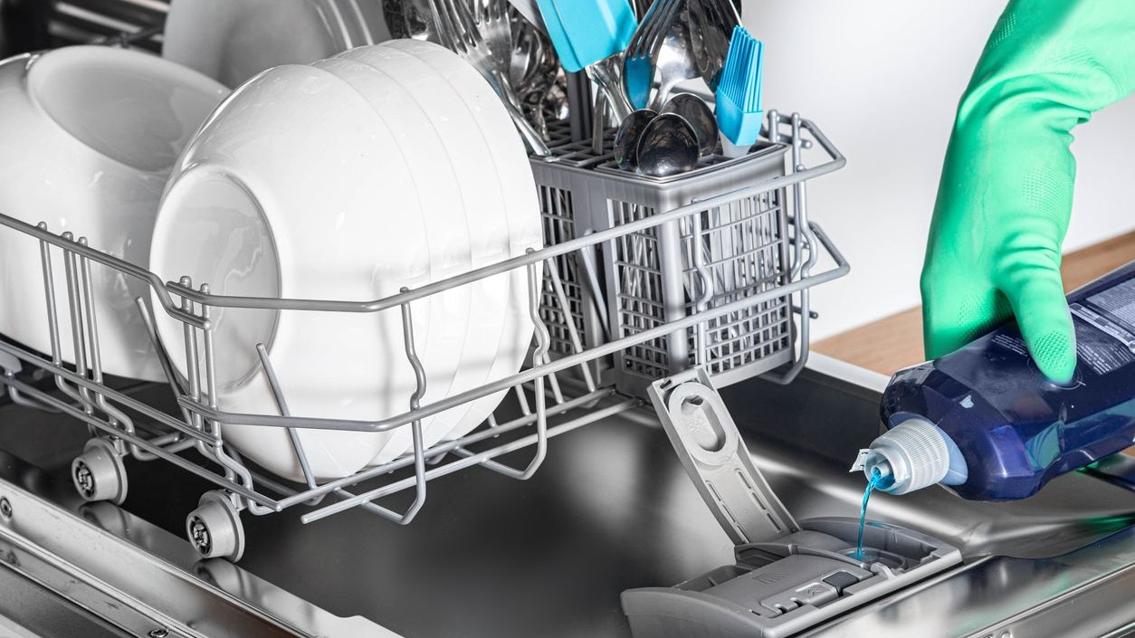Housewife add rinse aid to dishwasher for clean and shine dishes, close-up
