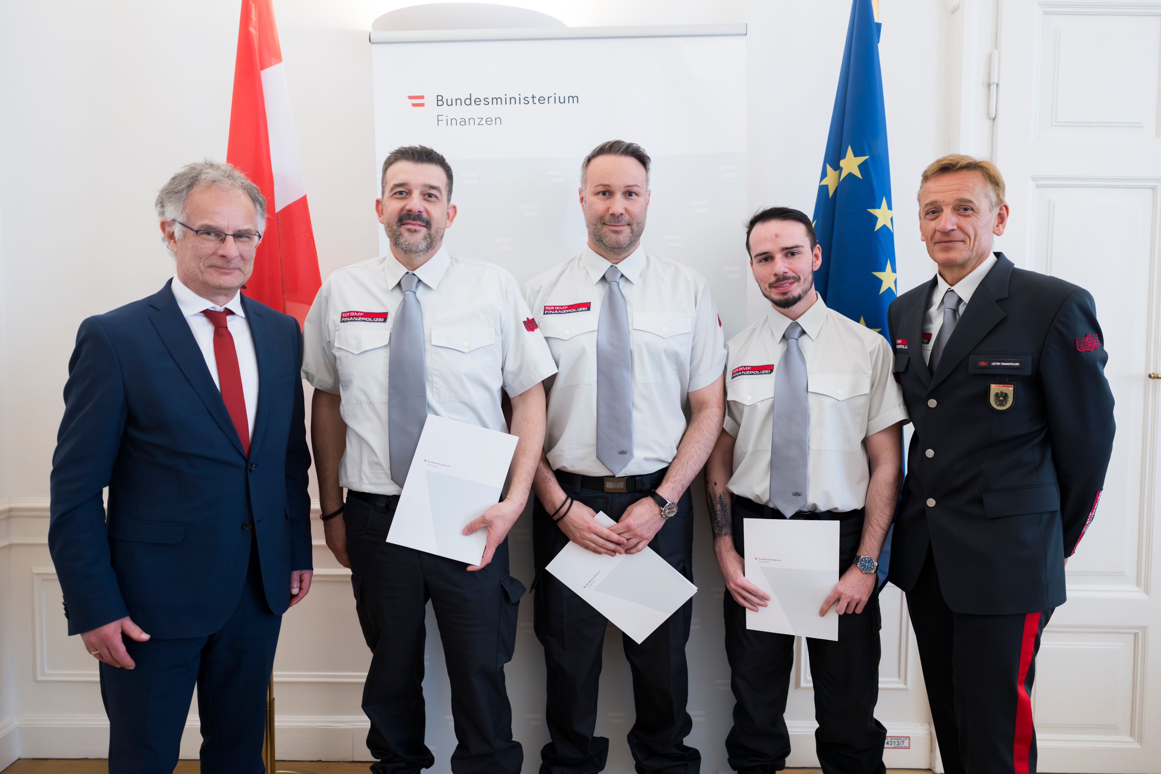 Finanzminister Markus Marterbauer (li.) ehrte drei Finanzpolizisten für ihren couragierten Einsatz bei einem Fahrzeugbrand auf der Nordbrücke.