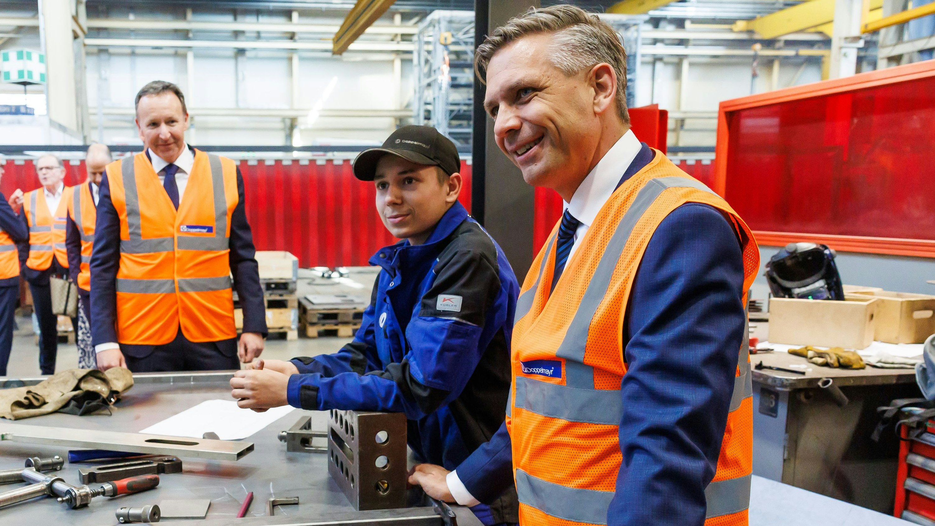 Wirtschaftsminister Hattmannsdorfer in Warnweste während einer Betriebsbesichtigung
