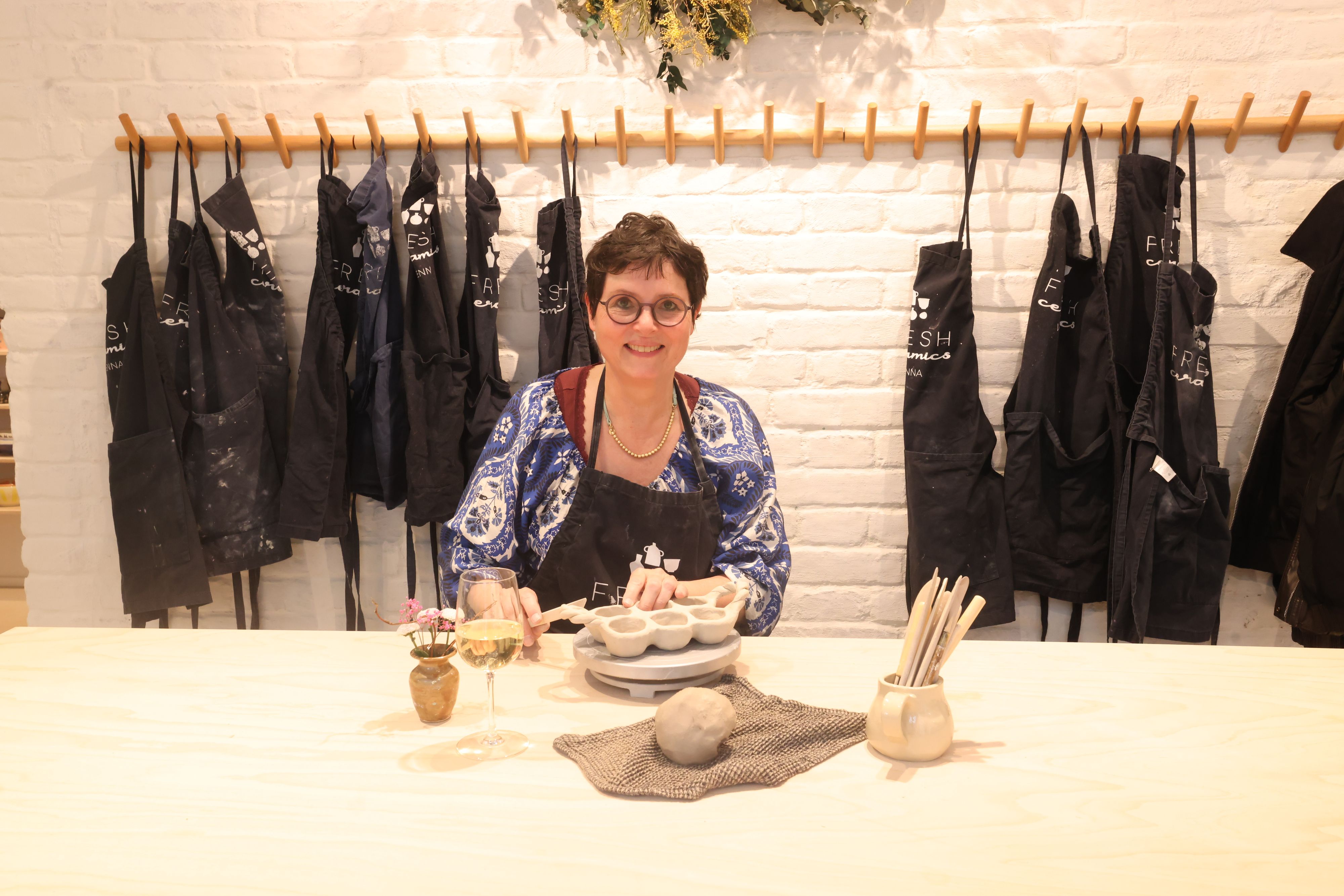 Profi Sabine erklärt den Kursteilnehmern bei einem Glas Wein das Wichtigste über das Arbeiten mit Ton.