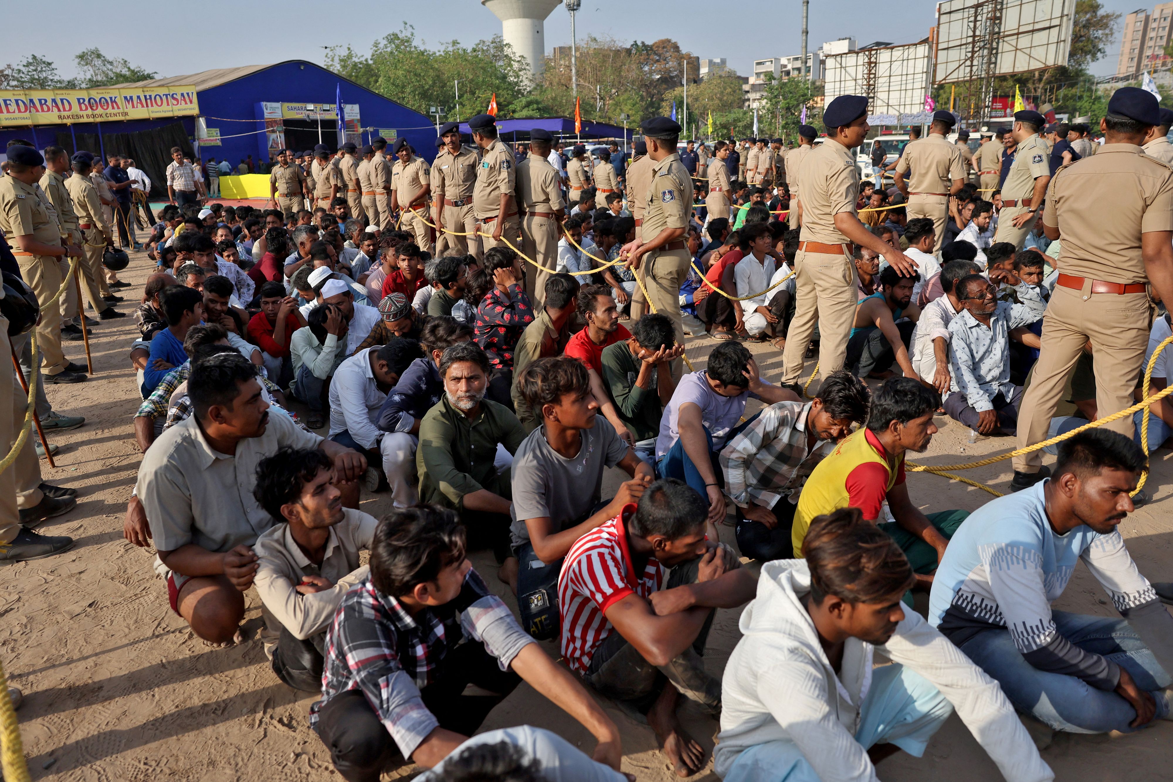 Polizisten stehen neben mutmaßlich pakistanischen Staatsbürgern ohne Papiere, nachdem sie bei Razzien in Ahmedabad festgenommen wurden.