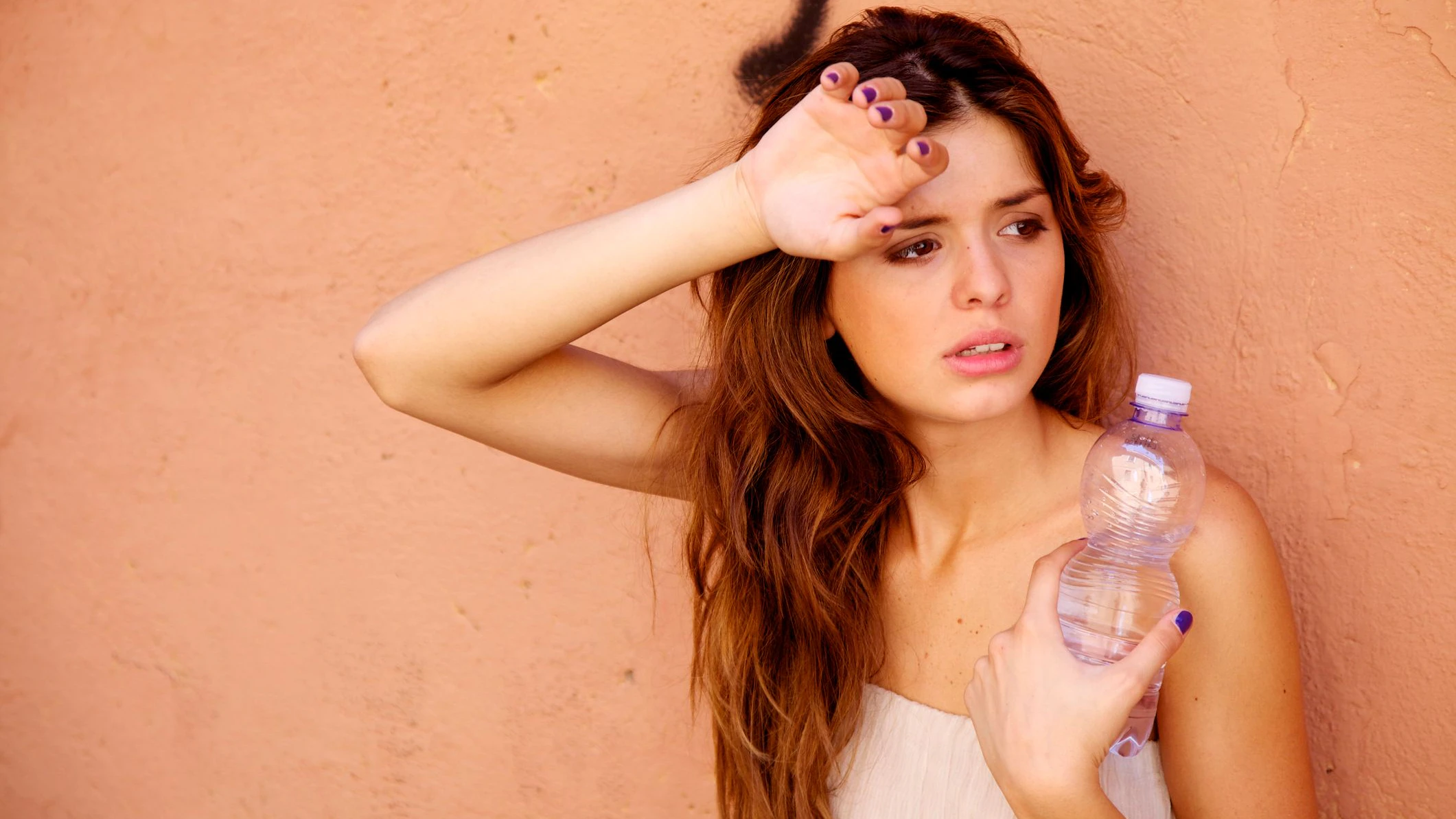 Young woman holding a bottle of mineral water on a hot summer day in Italy.