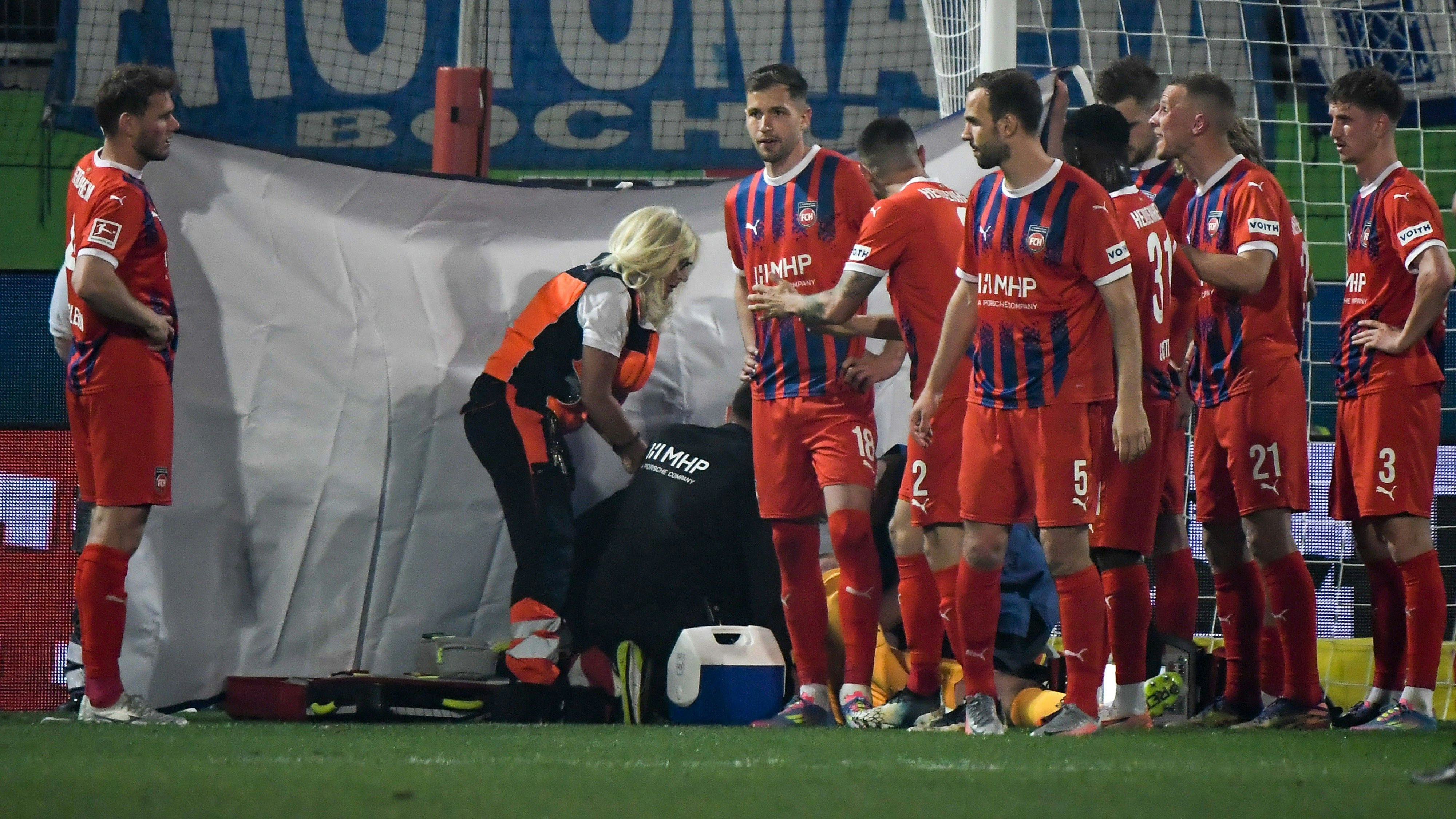 Teamärzte und Sanitäter kümmern sich um Heidenheim-Keeper Kevin Müller. . 