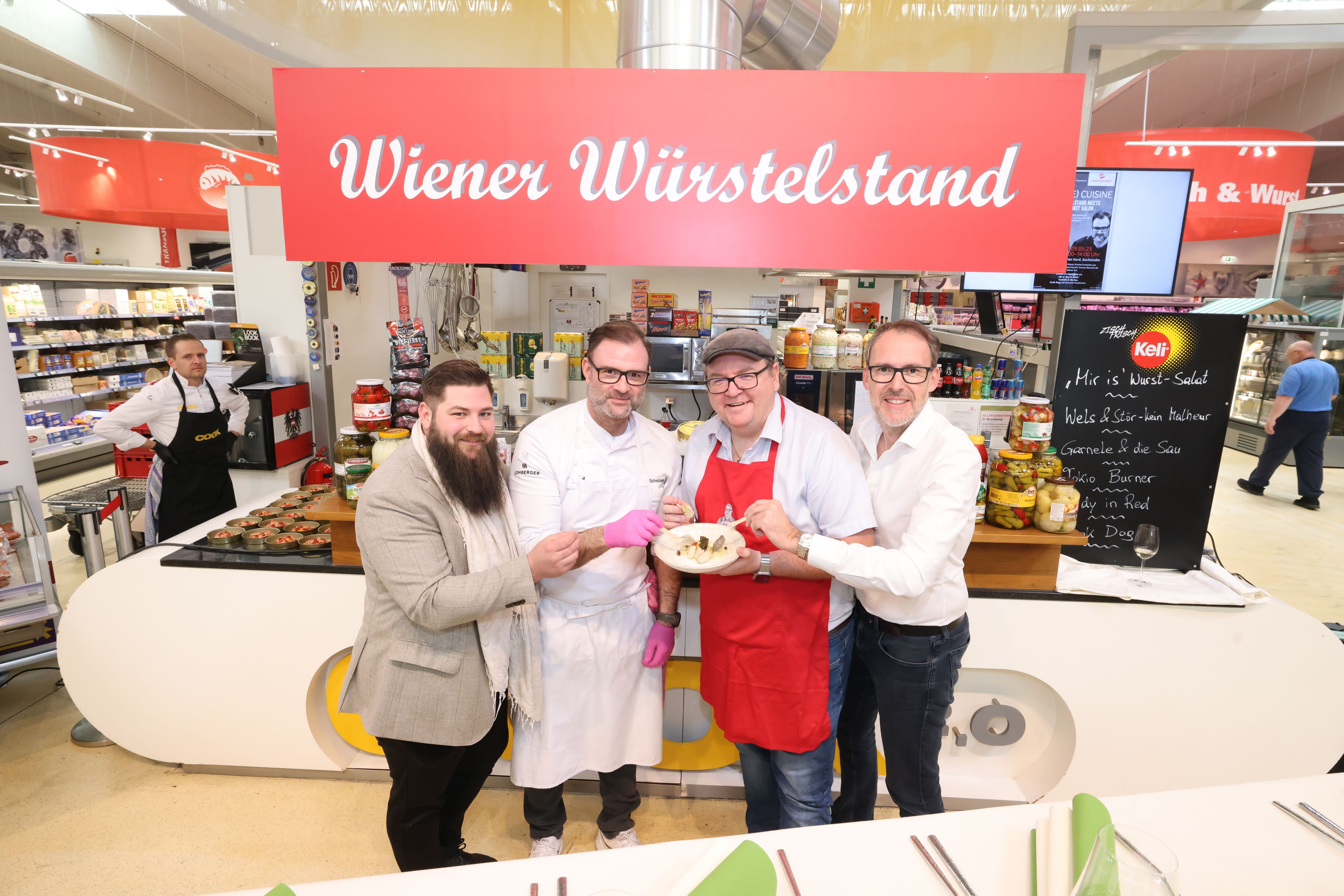 Wurst trifft Weltklasse: Spitzenkoch Oliver Scheiblauer (2. v. l.) und Würstel-Legende René Kachlir (mit Schürze) servieren Gourmet-Kreationen am Transgourmet-Würstelstand.