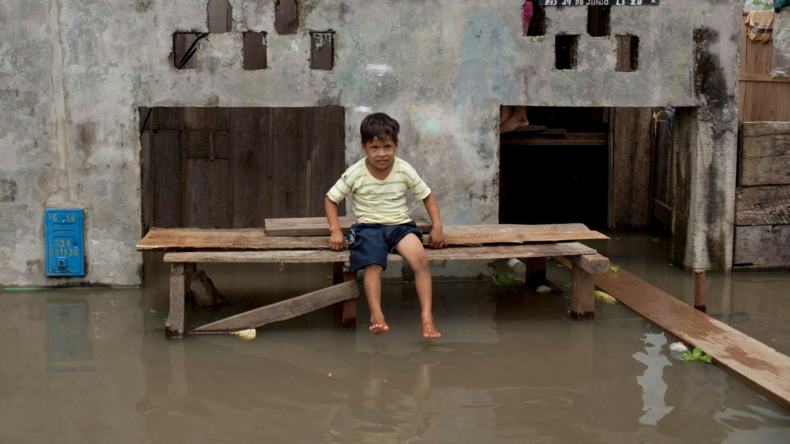 A boy sits outside his house surrounded by floodwaters at the district of Maynas, in Peru's Amazon city of Iquitos April 9, 2012. The jungle city is in a state of emergency, after being surrounded by the overflowing waters from the rivers of Nanay, Itaya and Amazon. The rivers have surpassed their record high and are three feet (0.91 metres) above the normal level. The health alert for dengue and malaria has been declared and about 60 improvised shelters located in schools, churches and community centres have been installed, local media reported. REUTERS/Musuk Nolte (PERU - Tags: DISASTER ENVIRONMENT SOCIETY)