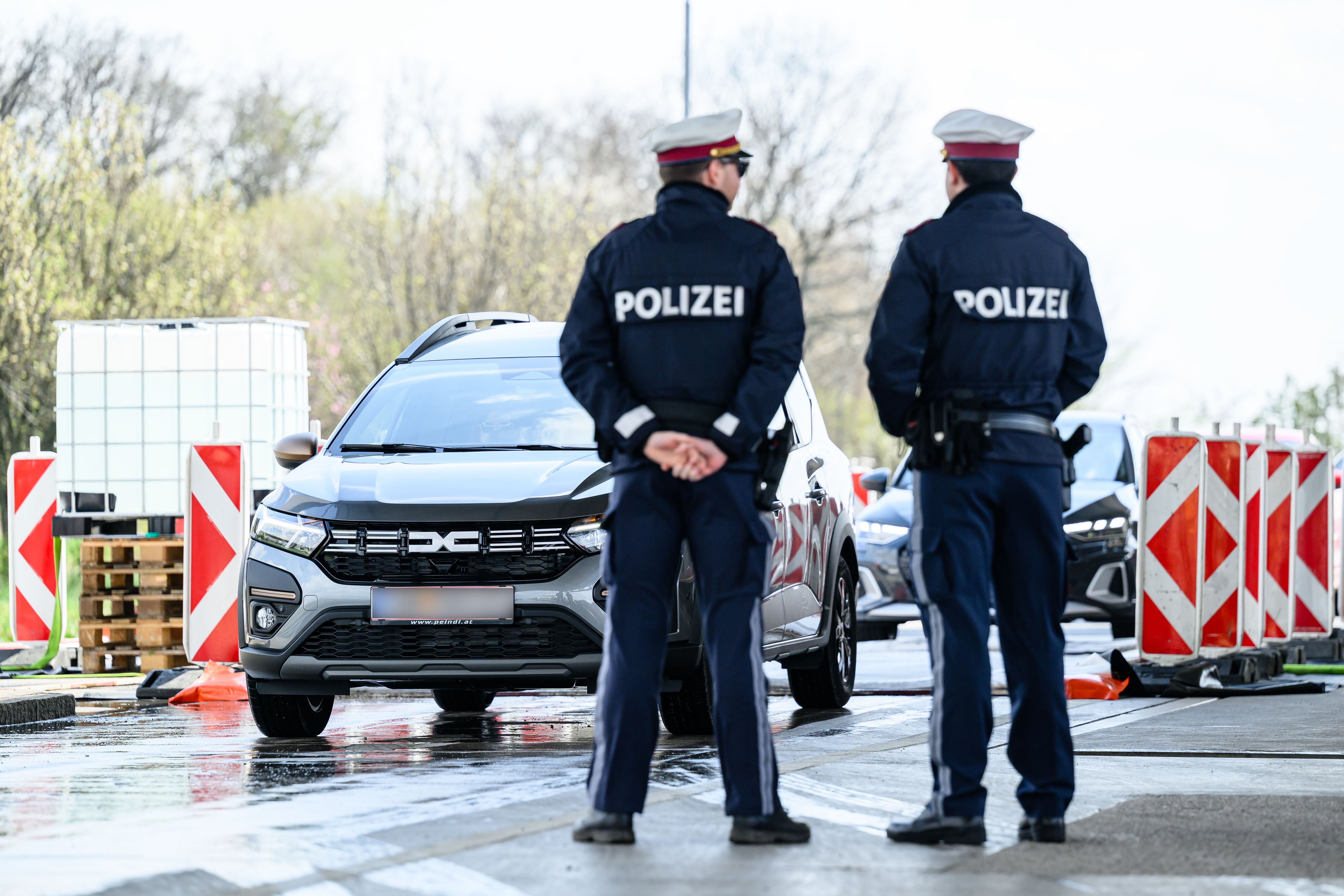 Polizisten überwachen PKW, die über den Seuchenteppich am Grenzübergang Klingenbach-Sopron fahren.