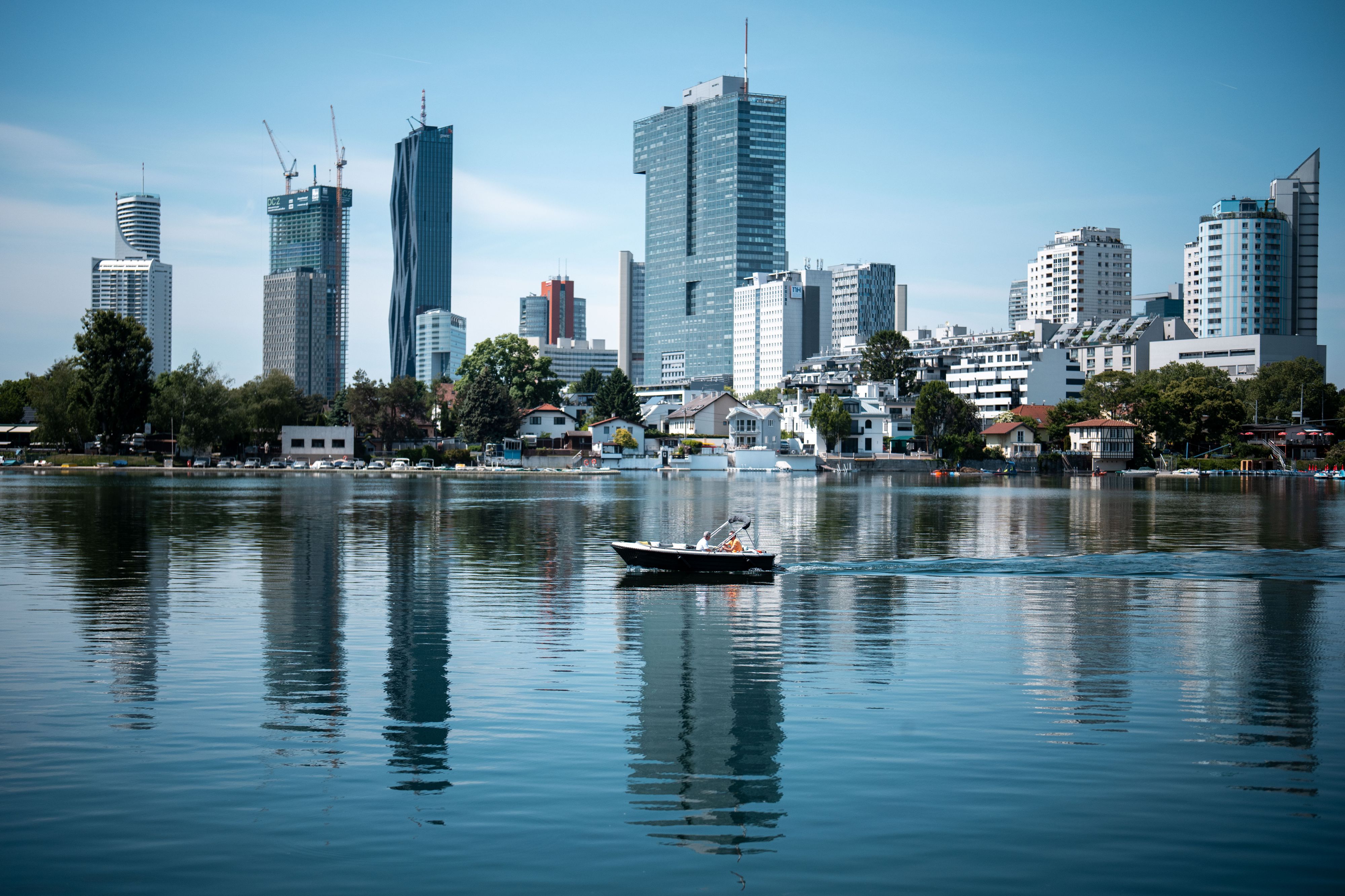 Ein Motorboot auf der Alten Donau in Wien, im Hintergrund die Gebäude auf der Donauplatte. Mai 2025