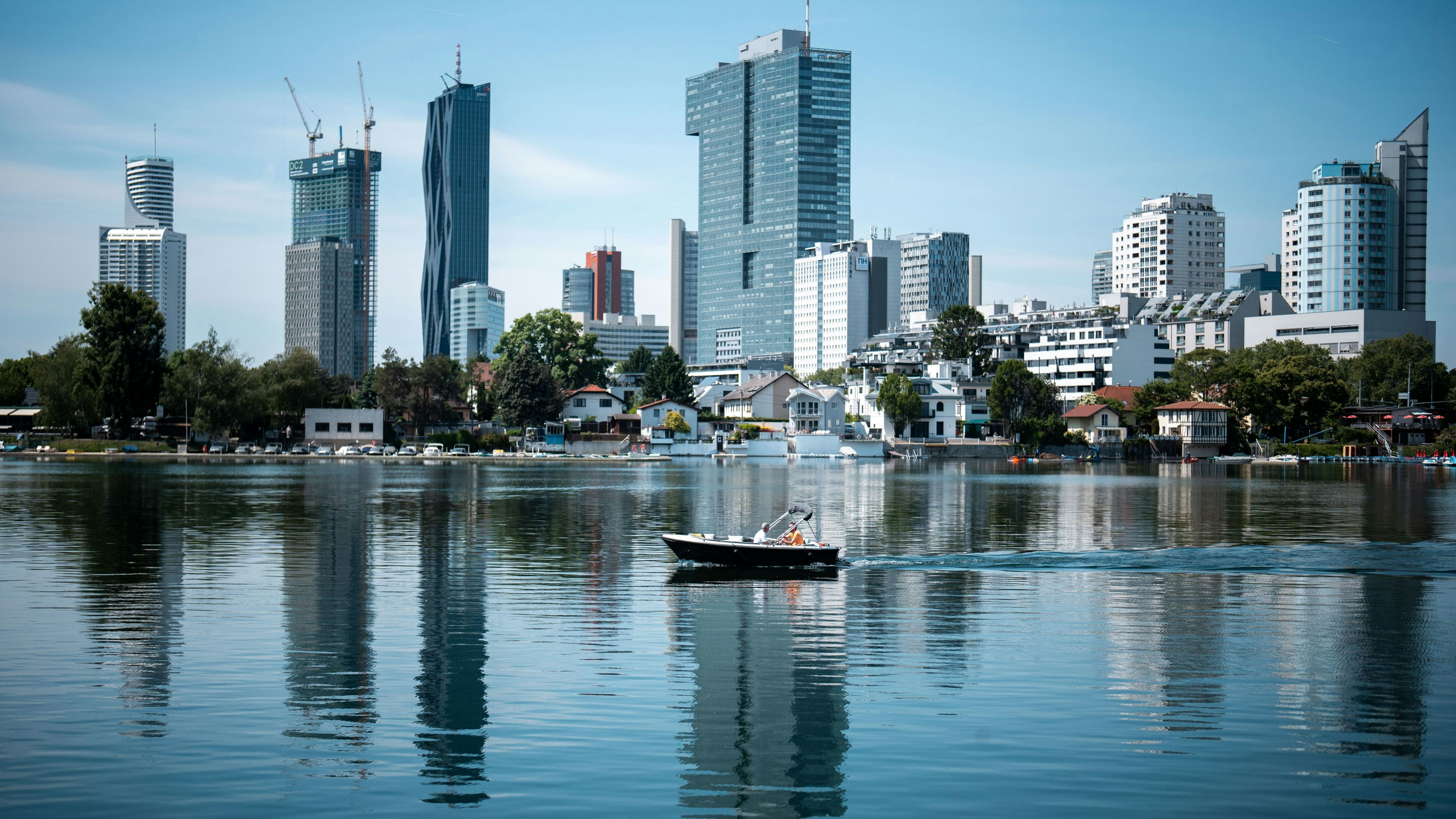 Ein Motorboot auf der Alten Donau in Wien, im Hintergrund die Gebäude auf der Donauplatte. Mai 2025