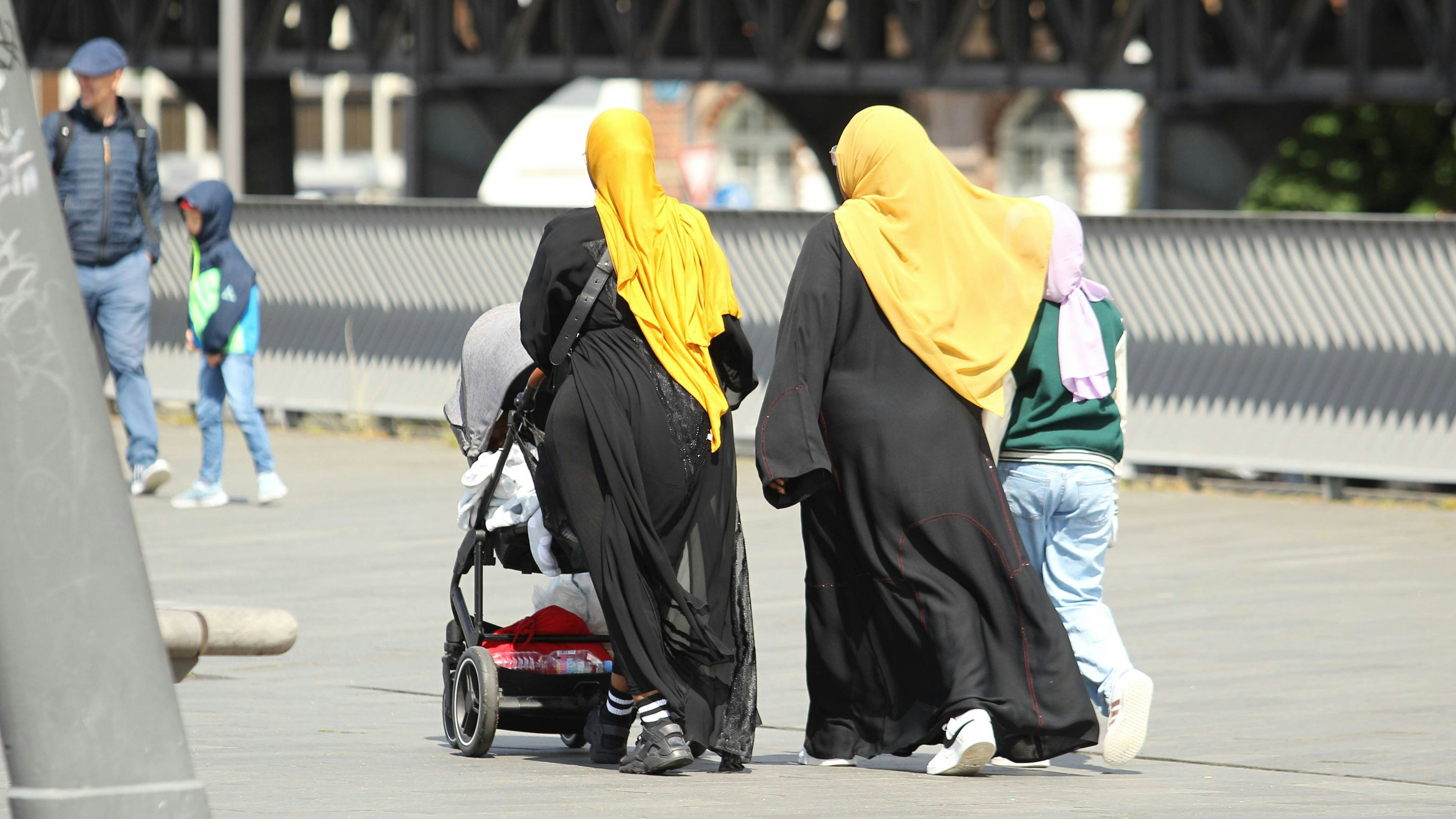 Zwei farbige Frauen gehen mit Kopftüchern bekleidet und einem Kinderwagen auf der Jan-Fedder-Promenade am Hamburger Hafen entlang. Neustadt Hamburg *** Two colored women walk along Jan Fedder Promenade at Hamburg harbor dressed with headscarves and a baby carriage Neustadt Hamburg