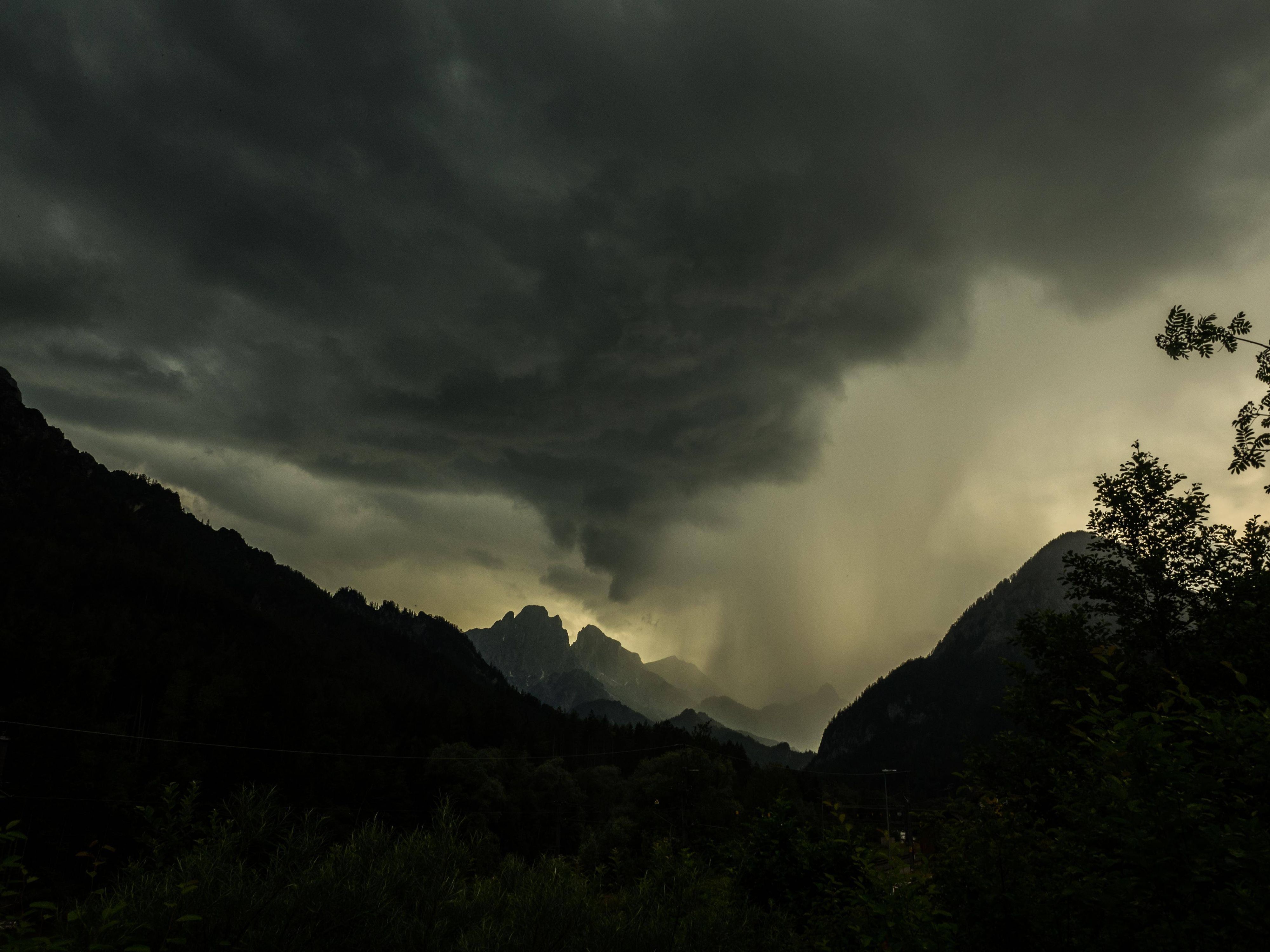 Gewitter und Regenwolken über Berggipfeln.