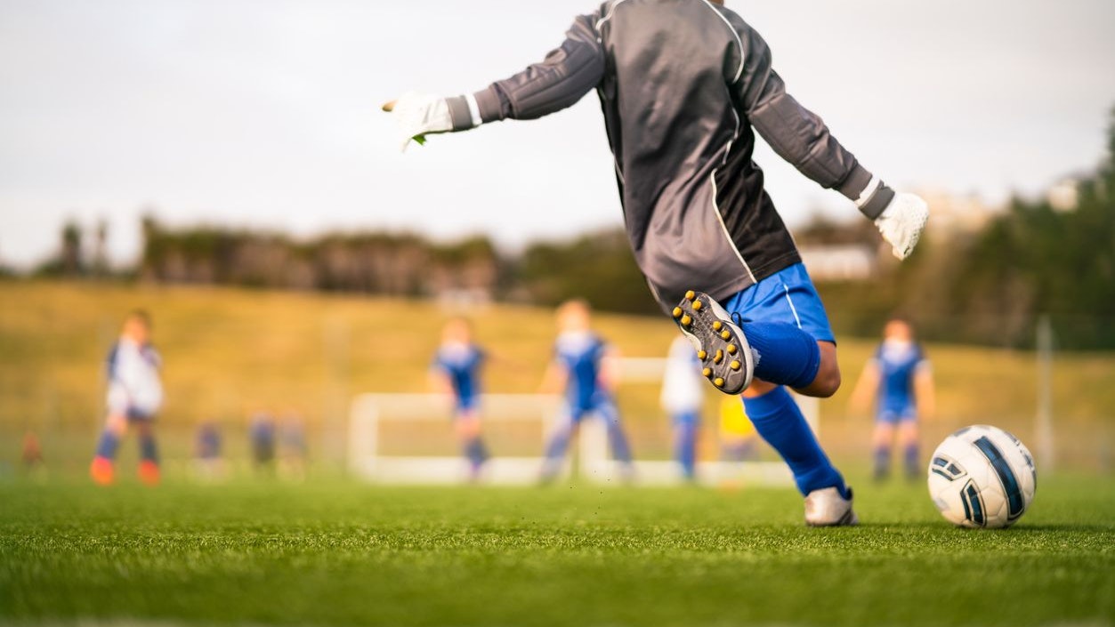 Little soccer player in soccer field playing soccer outdoor in casual clothing.